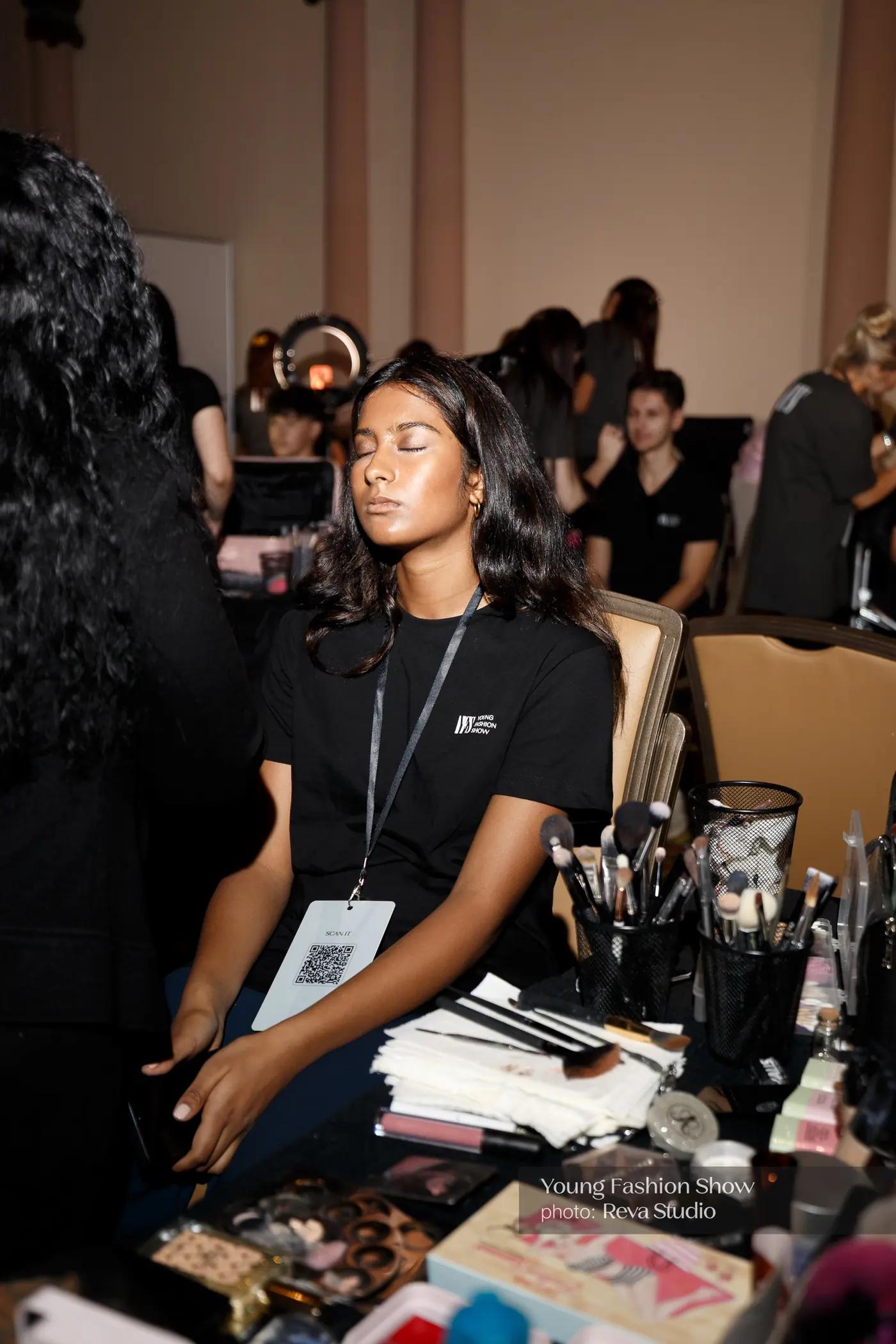 Participant seated at a backstage beauty station