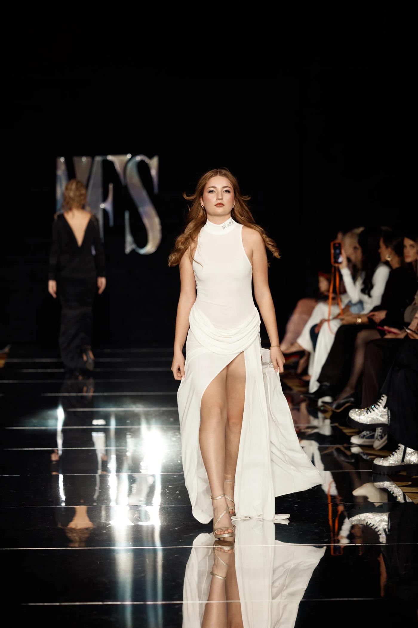 A model in a white gown walking the YFS runway