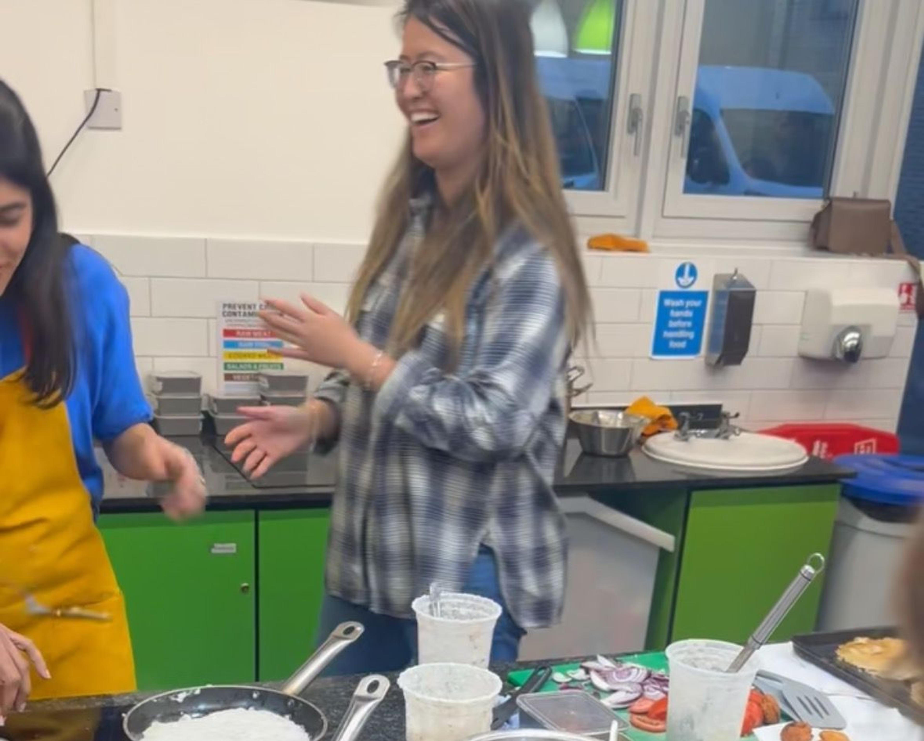 Guests laughing while cooking at a prep station lined with ingredients and pans