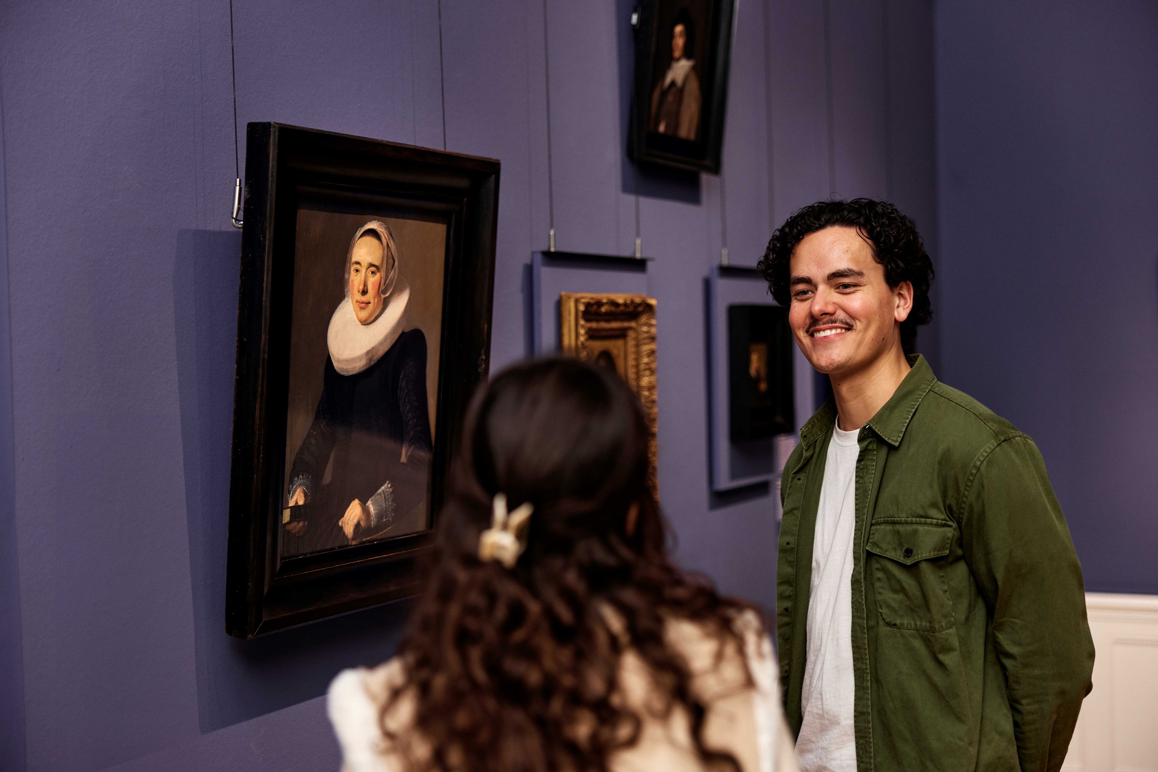 Man and woman looking at a painting by Judith Leyster.