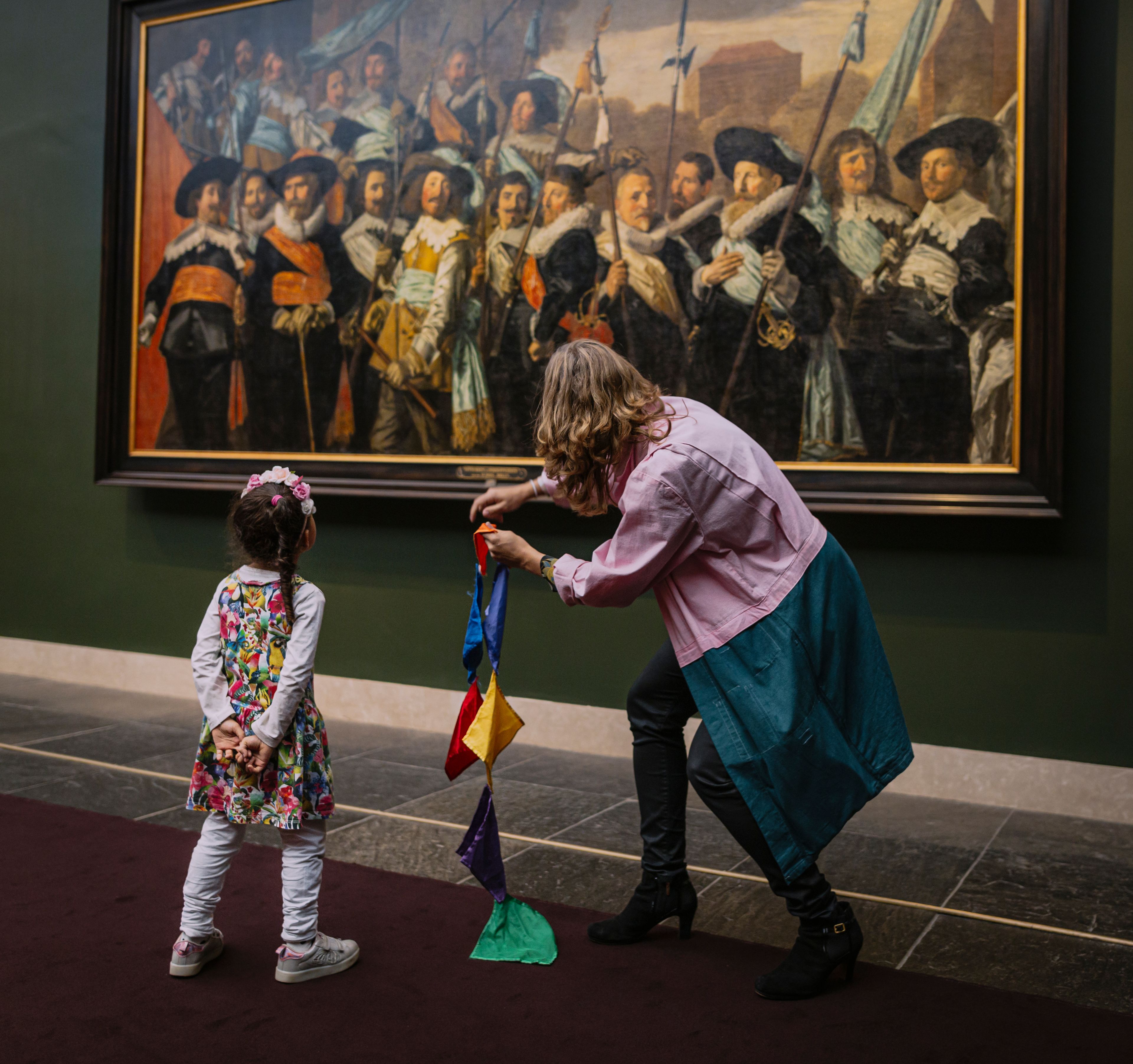 Rondleiding Sjaak Suppoost, kindje meet samen met de rondleider het grootste schilderij van het Frans Hals Museum op.