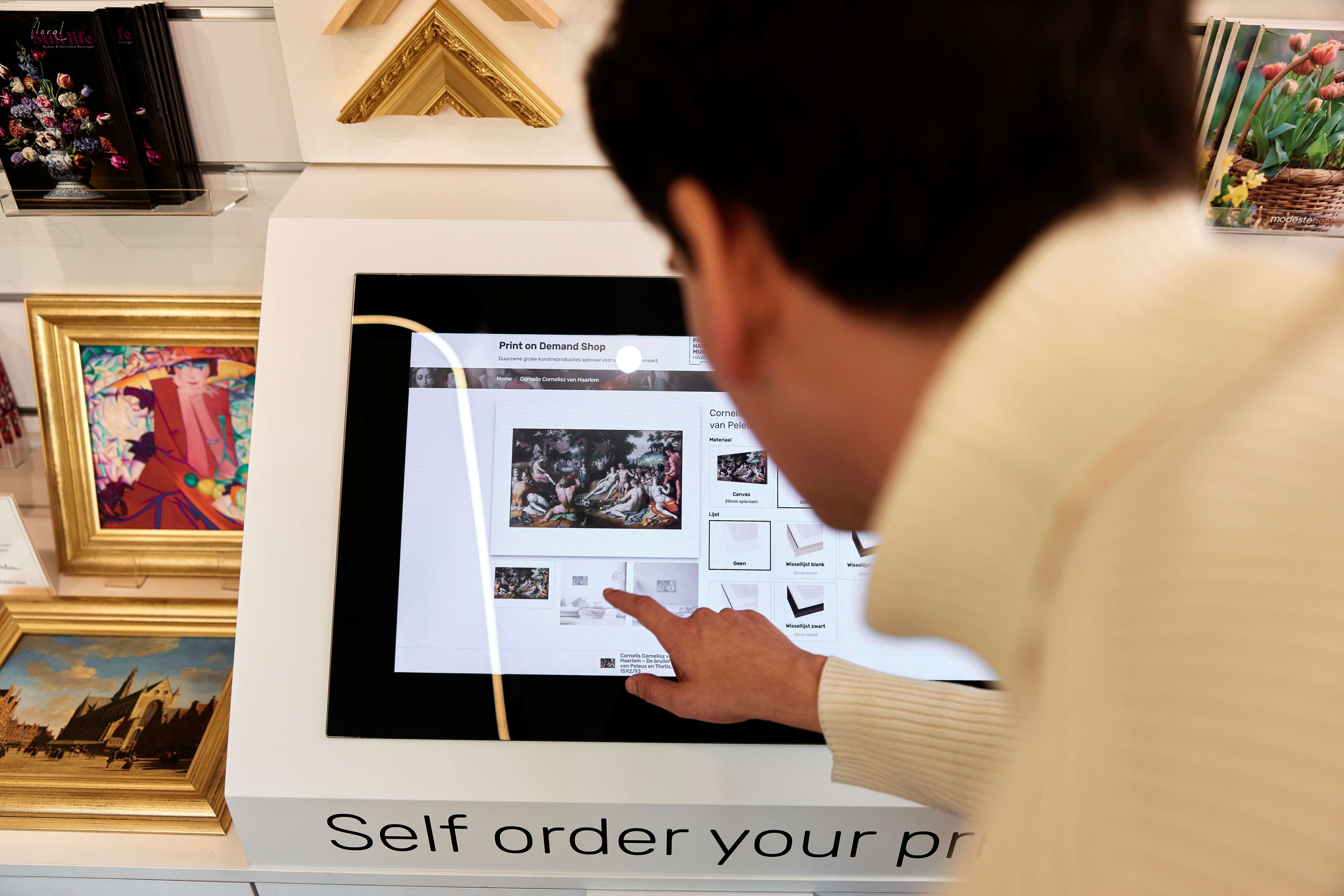 Mannelijke bezoeker bekijkt de opties voor Print on Demand in de museumwinkel.