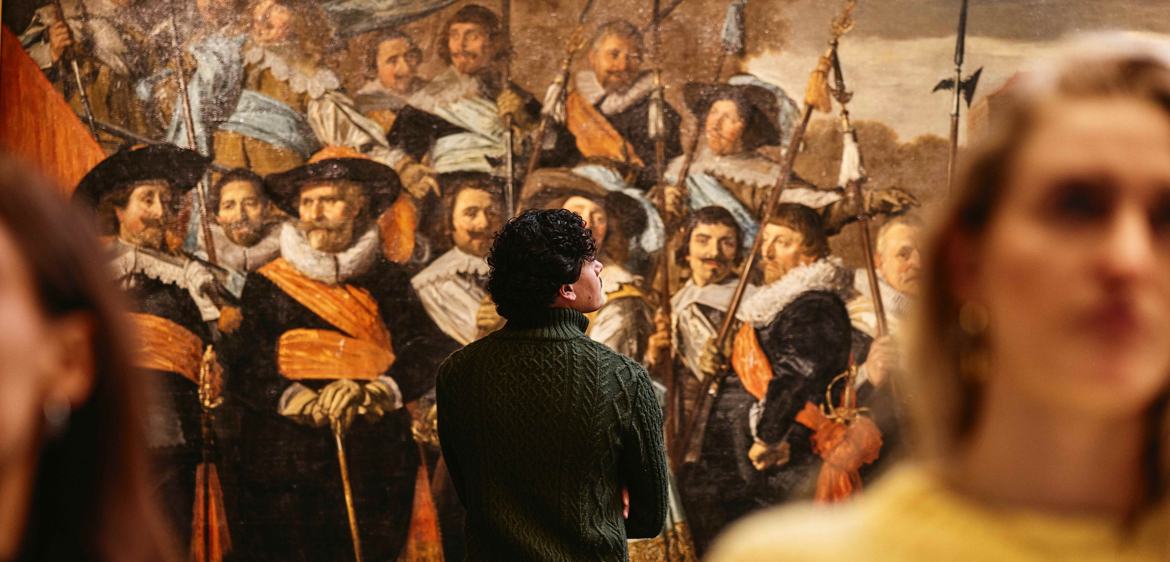 Mannelijke bezoeker kijkt naar een van de schuttersstukken van Frans Hals in het Frans Hals Museum.