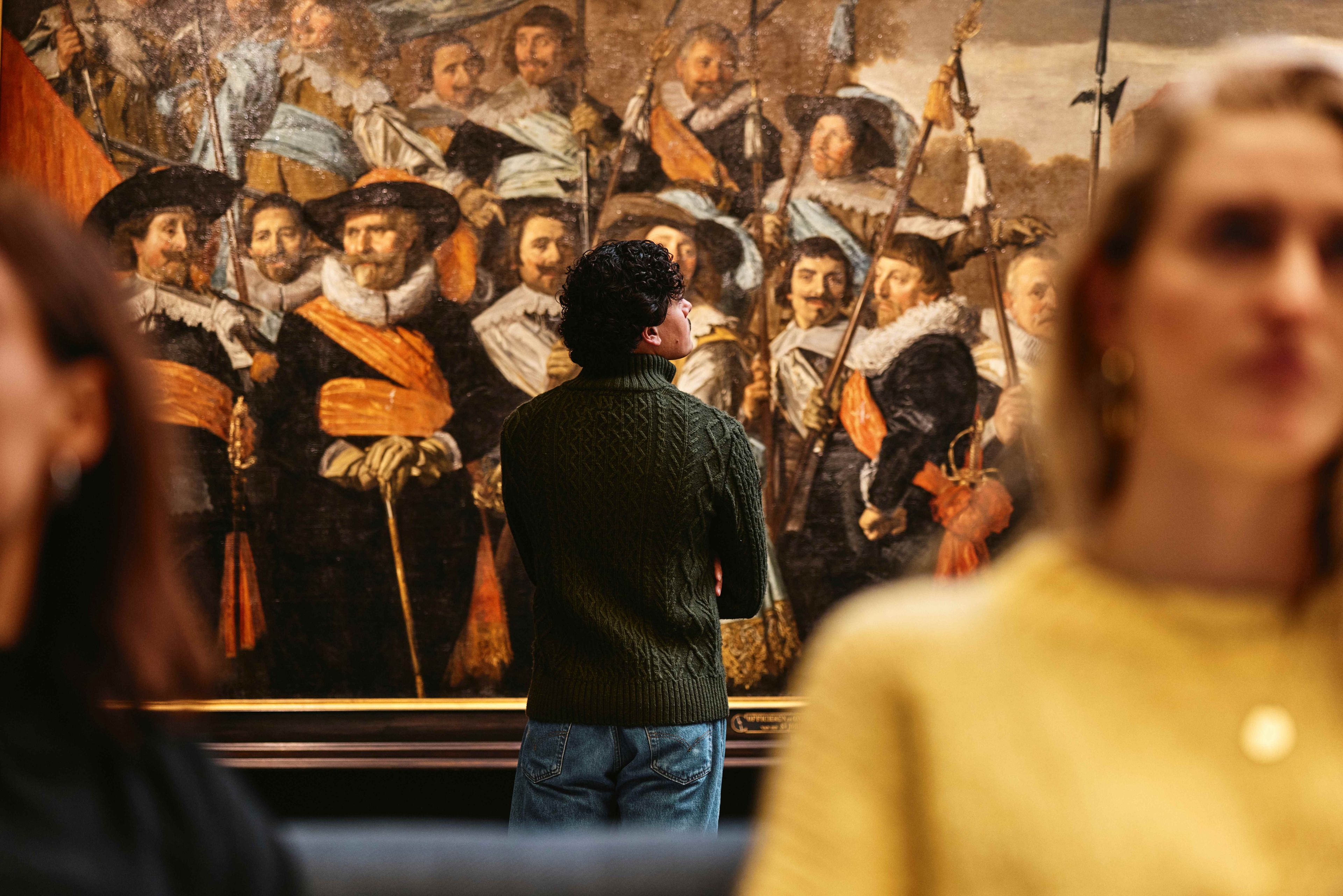 Visitor looking at a group portrait of civic guards by Frans Hals at the Frans Hals Museum.