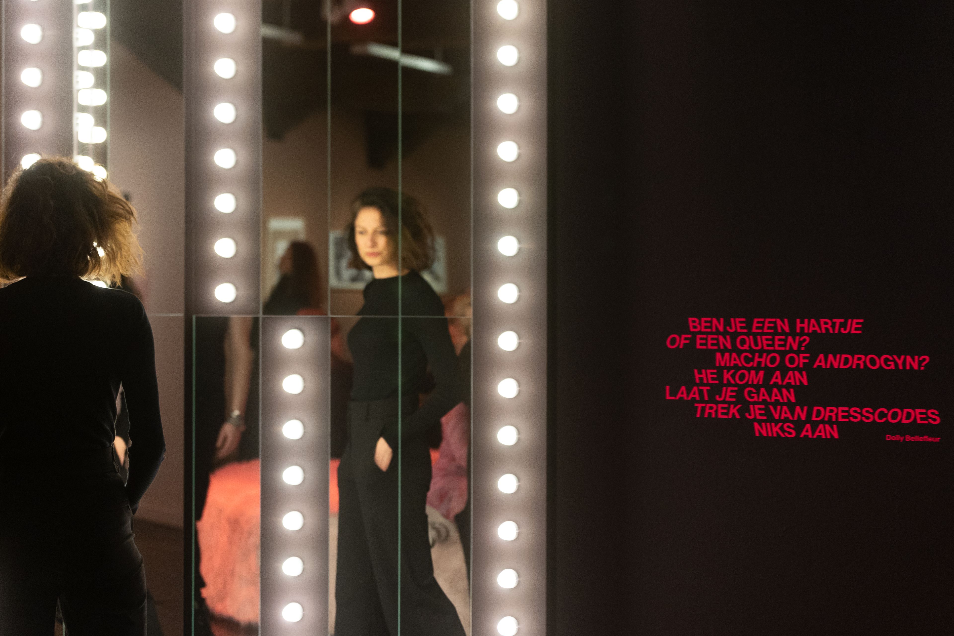 Vrouwelijke bezoeker kijkt in de spiegel bij de opening van de tentoonstelling The Art of Drag in HAL.