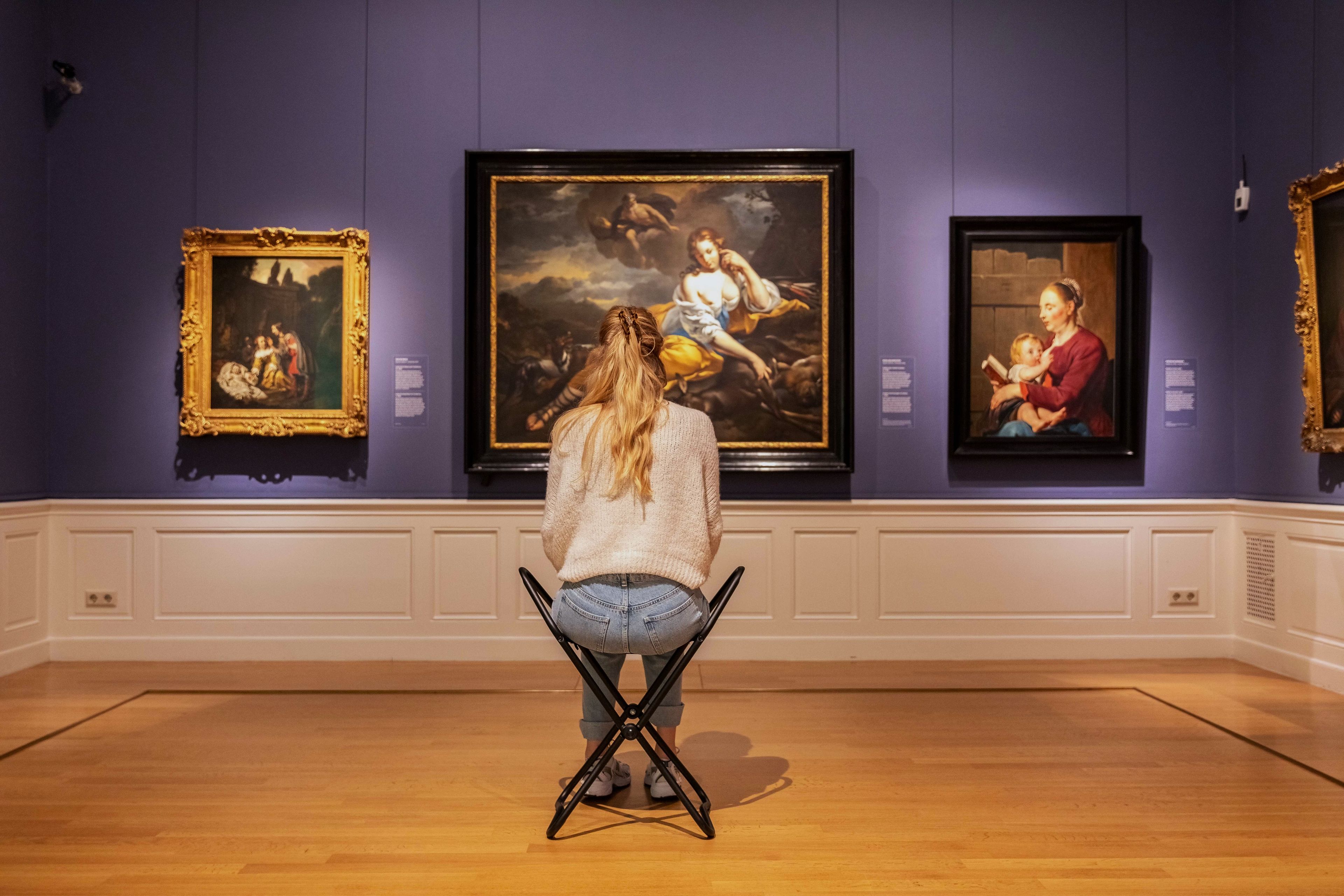 Visitor on a stool in front of a picture wall at Frans Hals Museum.