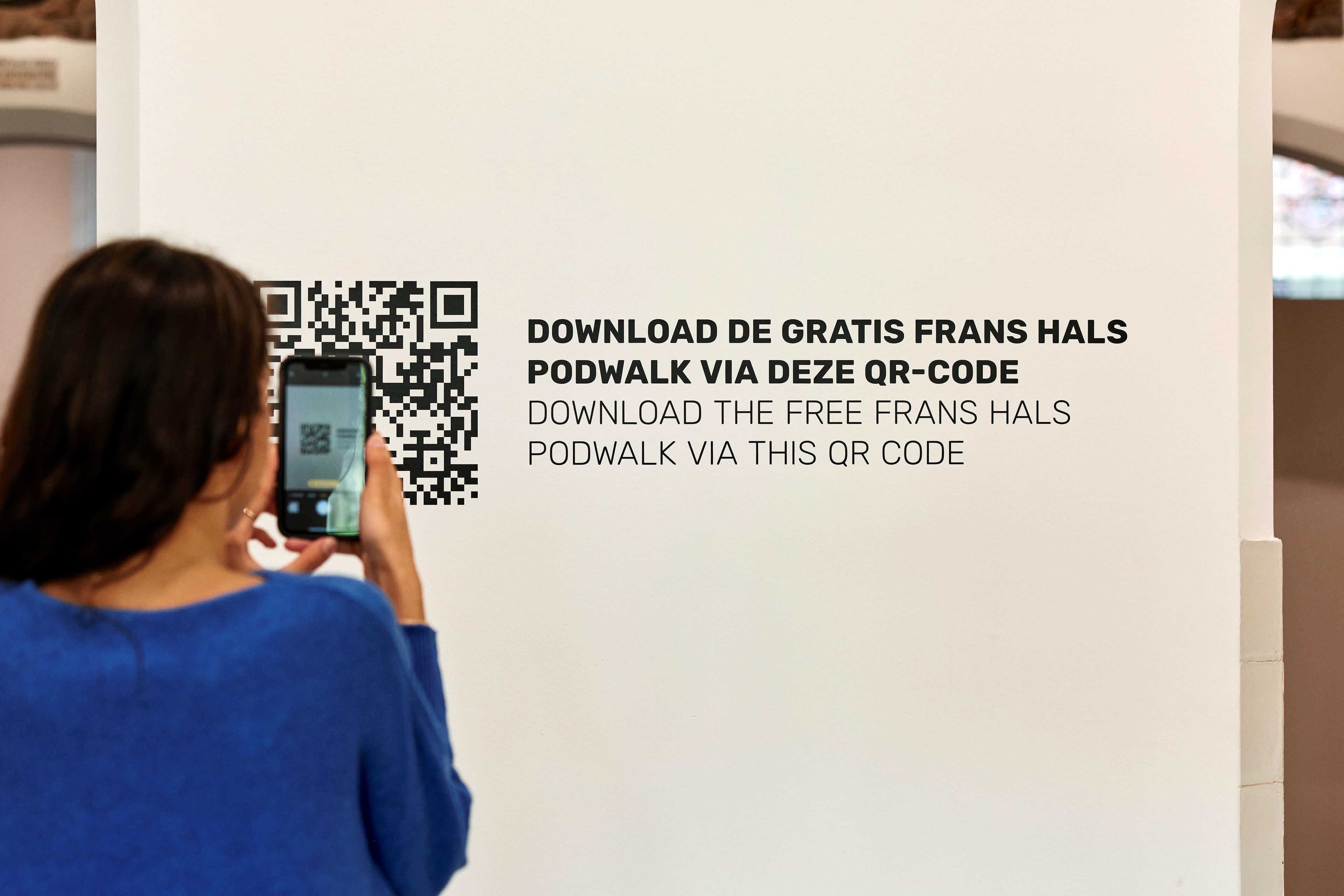Visitor scanning the podwalk QR code on the wall of the Frans Hals Museum hall.