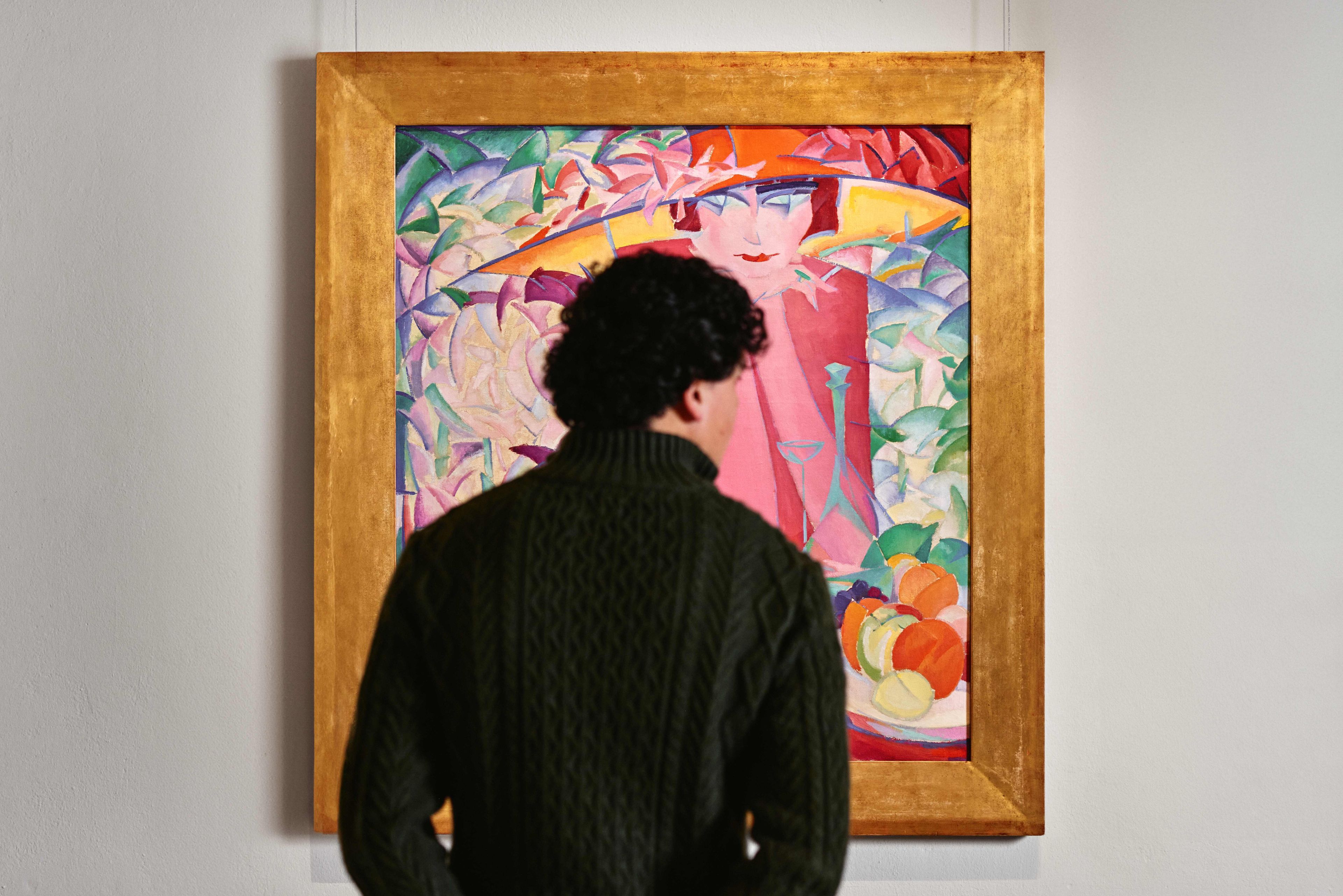 Mannelijke bezoeker bekijkt het kunstwerk 'Dame met grote hoed in prieel' van Leo Gestel.