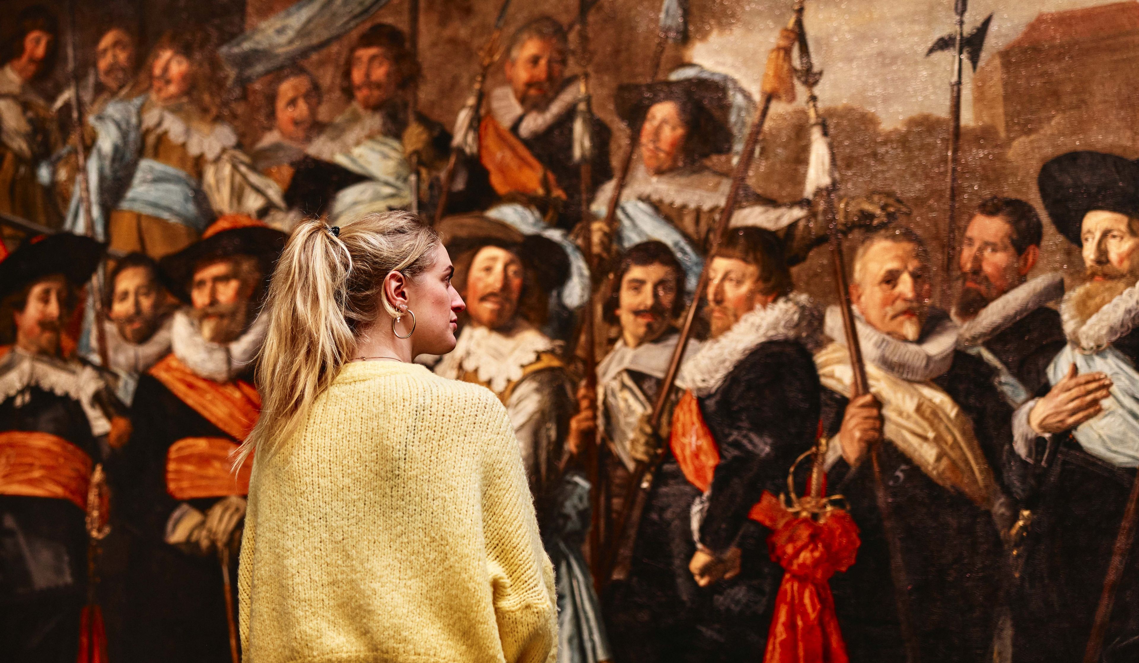 Vrouwelijke bezoeker bekijkt schuttersstuk van Frans Hals.