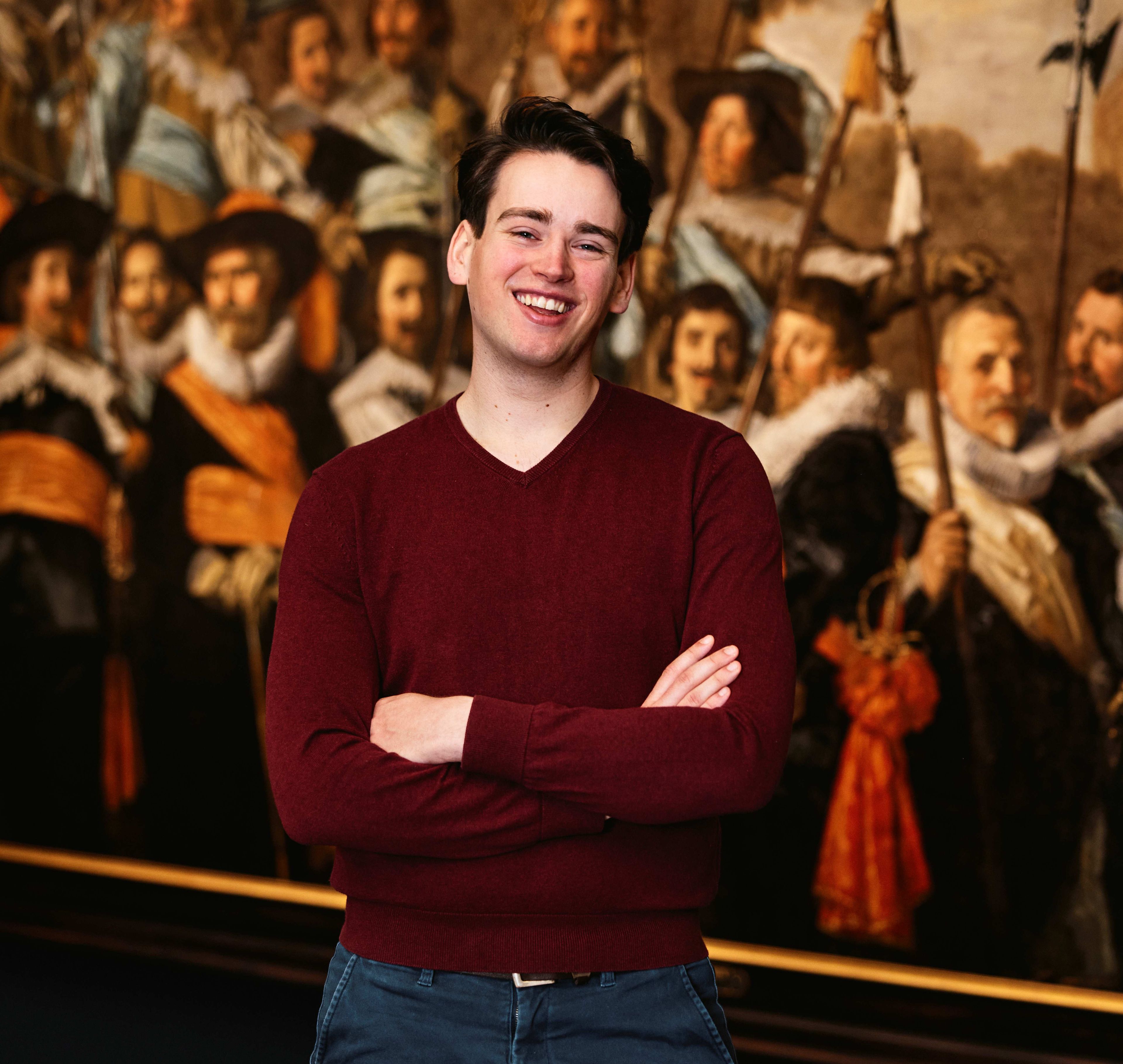 Mannelijke bezoeker poseert voor een schuttersstuk van Frans Hals in het Frans Hals Museum.