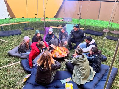 Menschen sitzen in einem Zelt ums Feuer