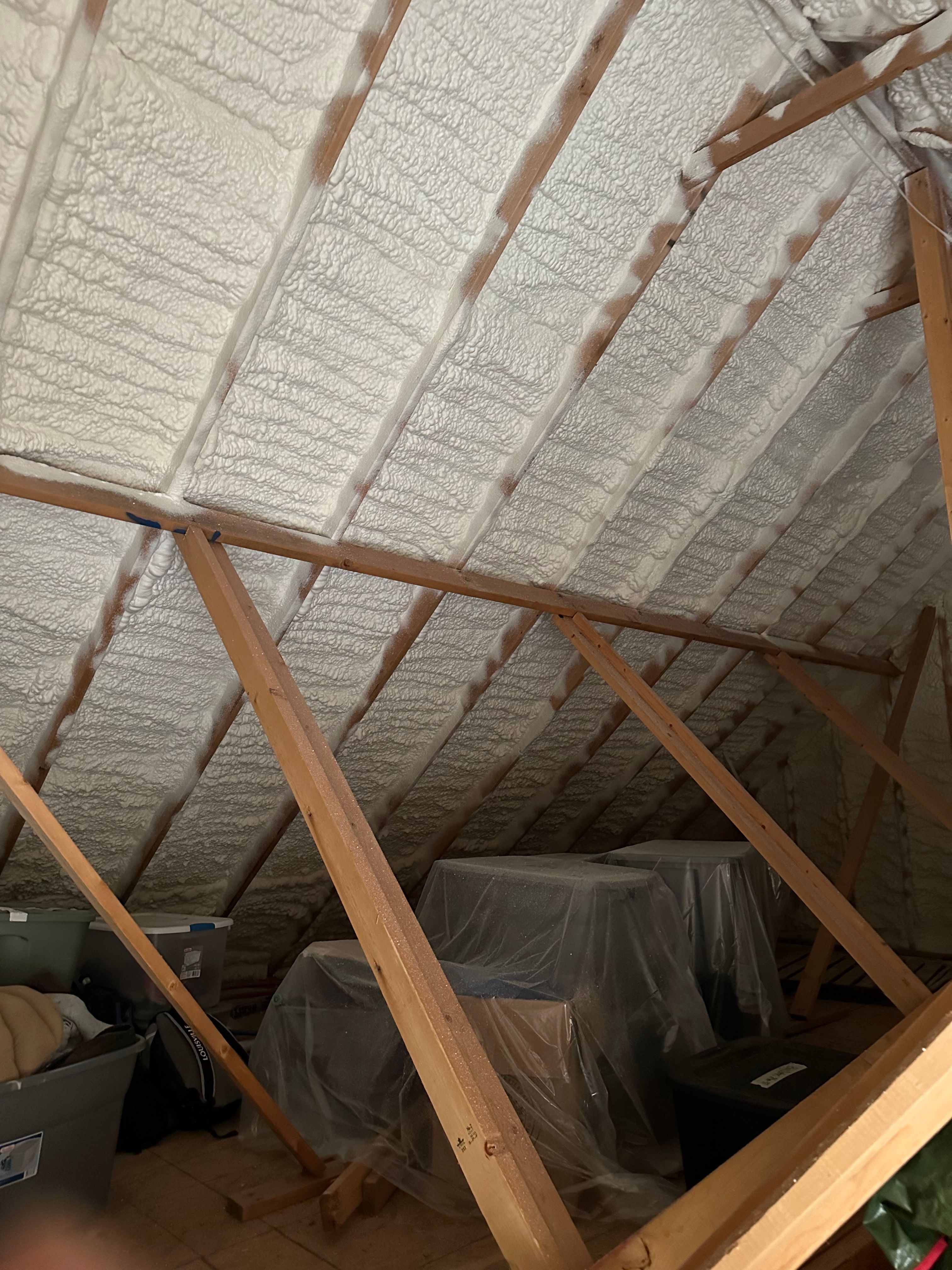 Spray foam sealing the roofline of an attic