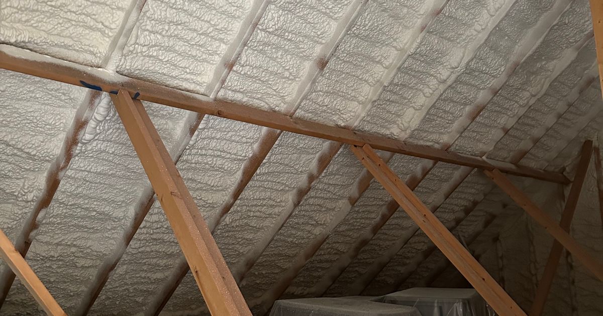 Spray foam sealing the roofline of an attic