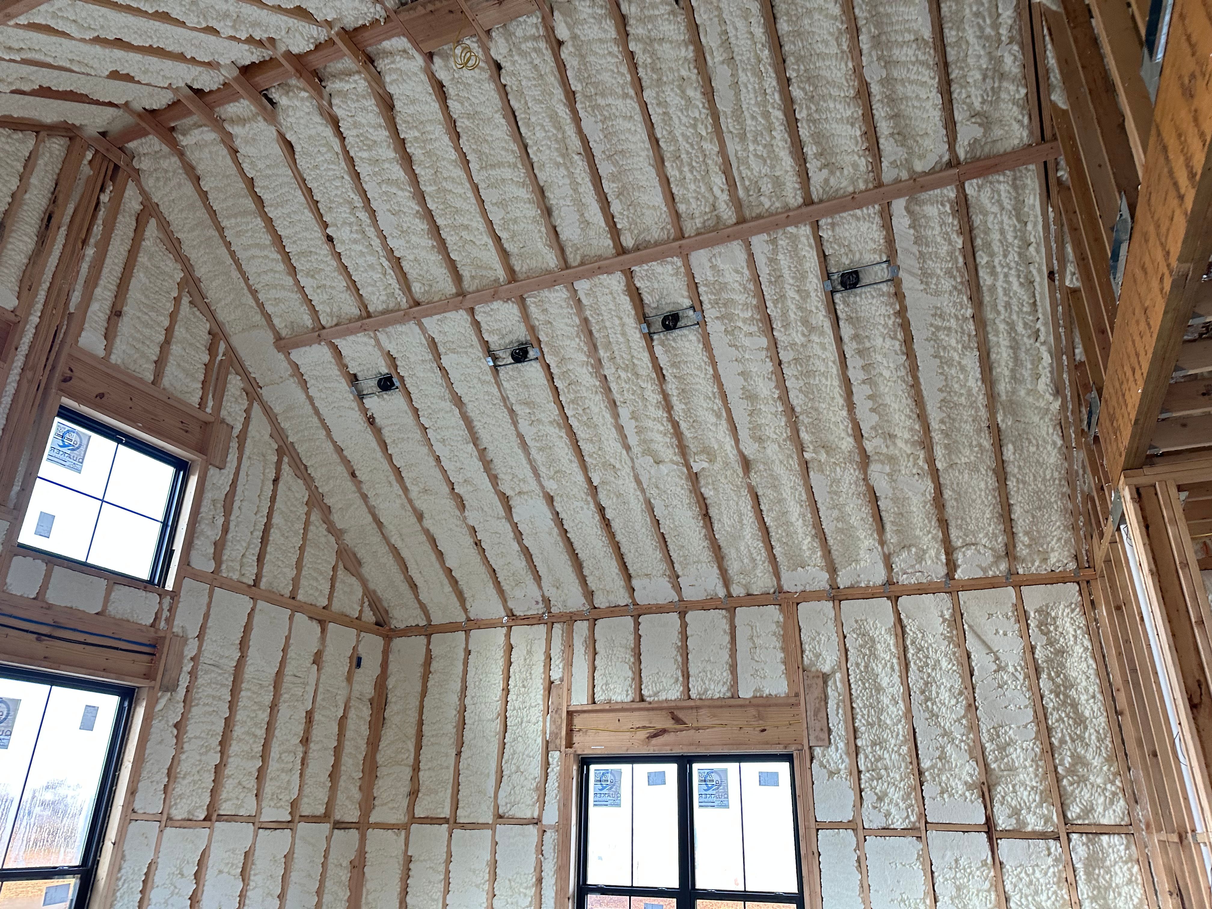 Open cell spray foam covering the walls and vaulted ceiling of a new construction home in Northwest Arkansas