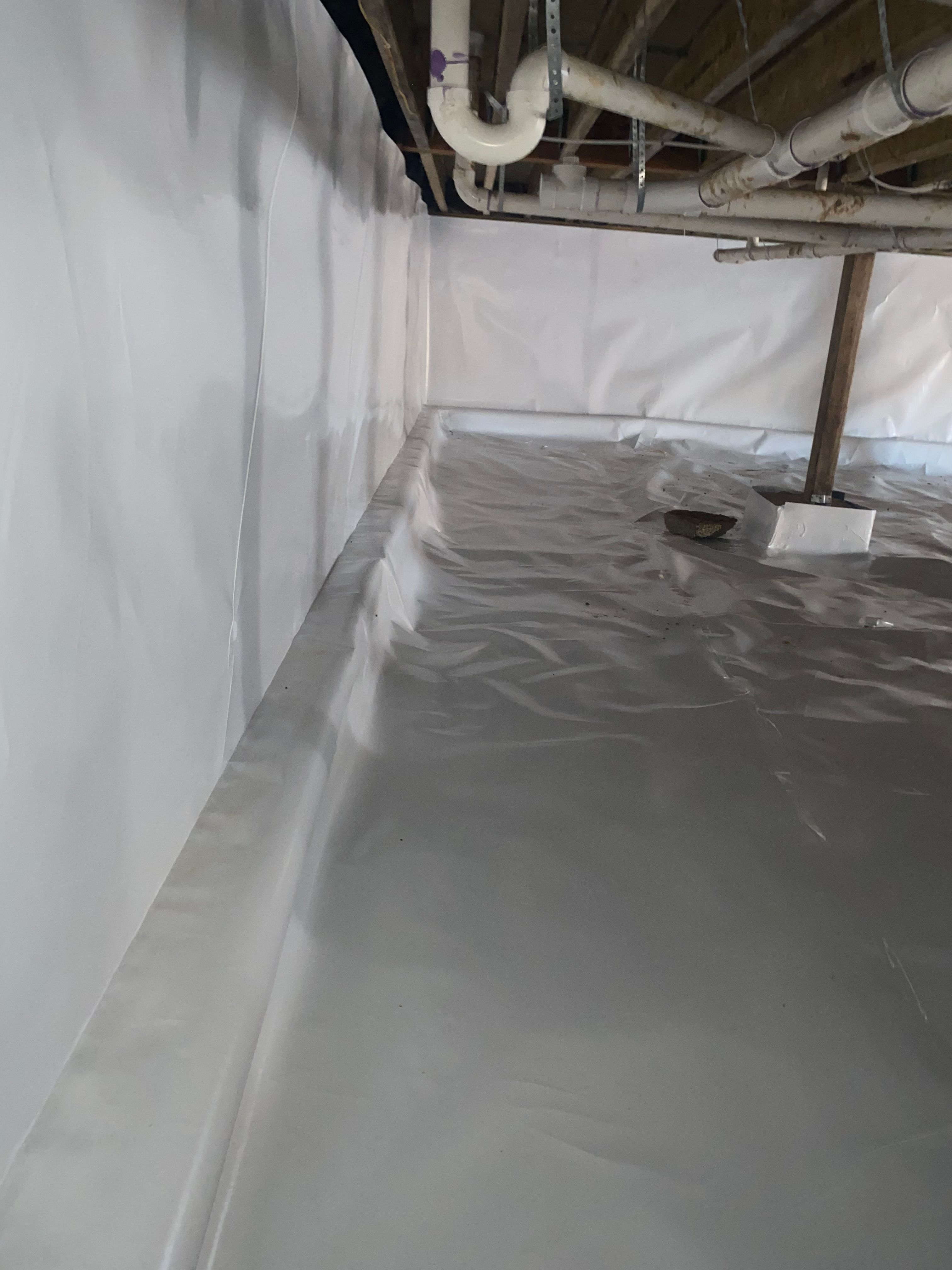 Finished crawl space encapsulation with a sealed white vapor barrier on the floor, walls, and piers
