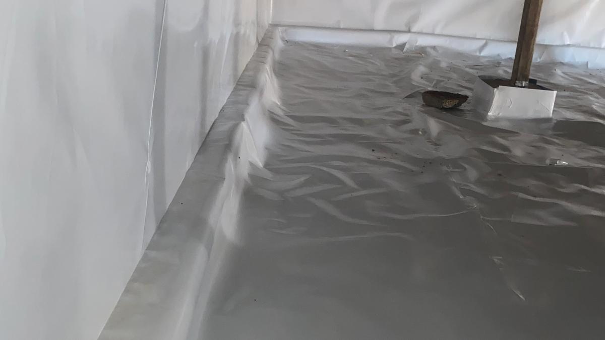 Finished crawl space encapsulation with a sealed white vapor barrier on the floor, walls, and piers