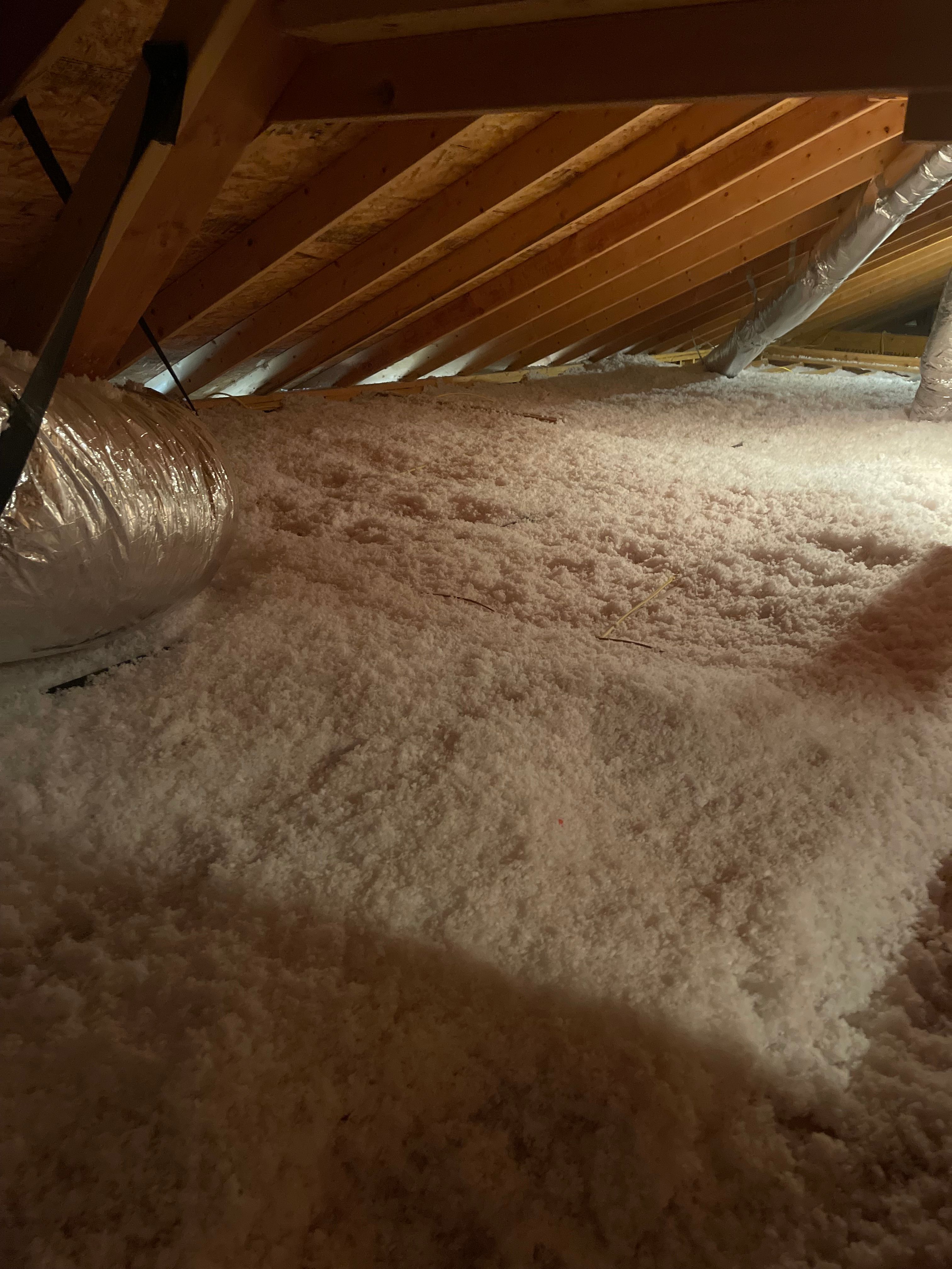 Blown-in fiberglass attic insulation installed to full depth around wrapped ductwork