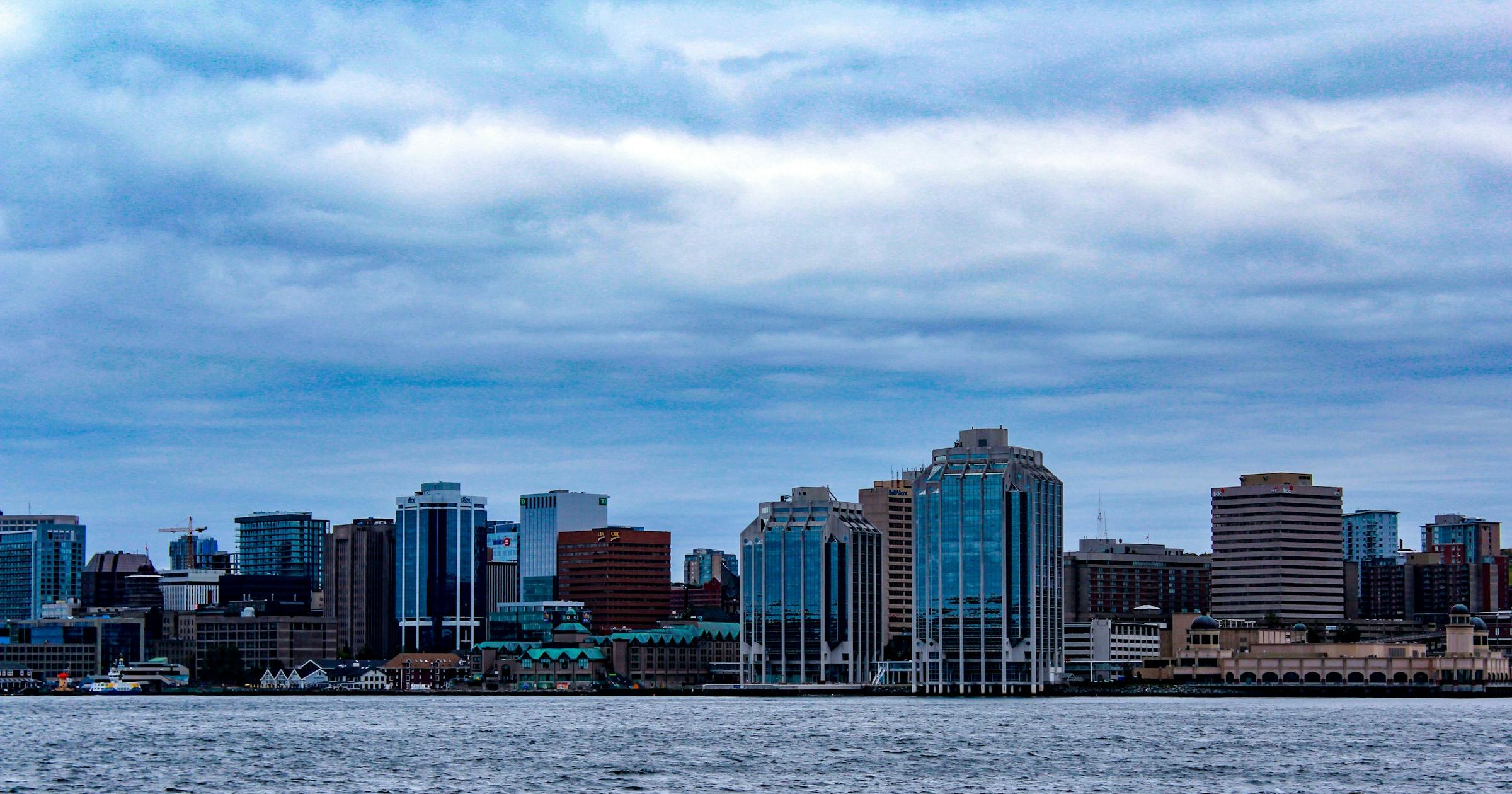 Halifax waterfront with downtown buildings across calm harbour water under a cloudy sky