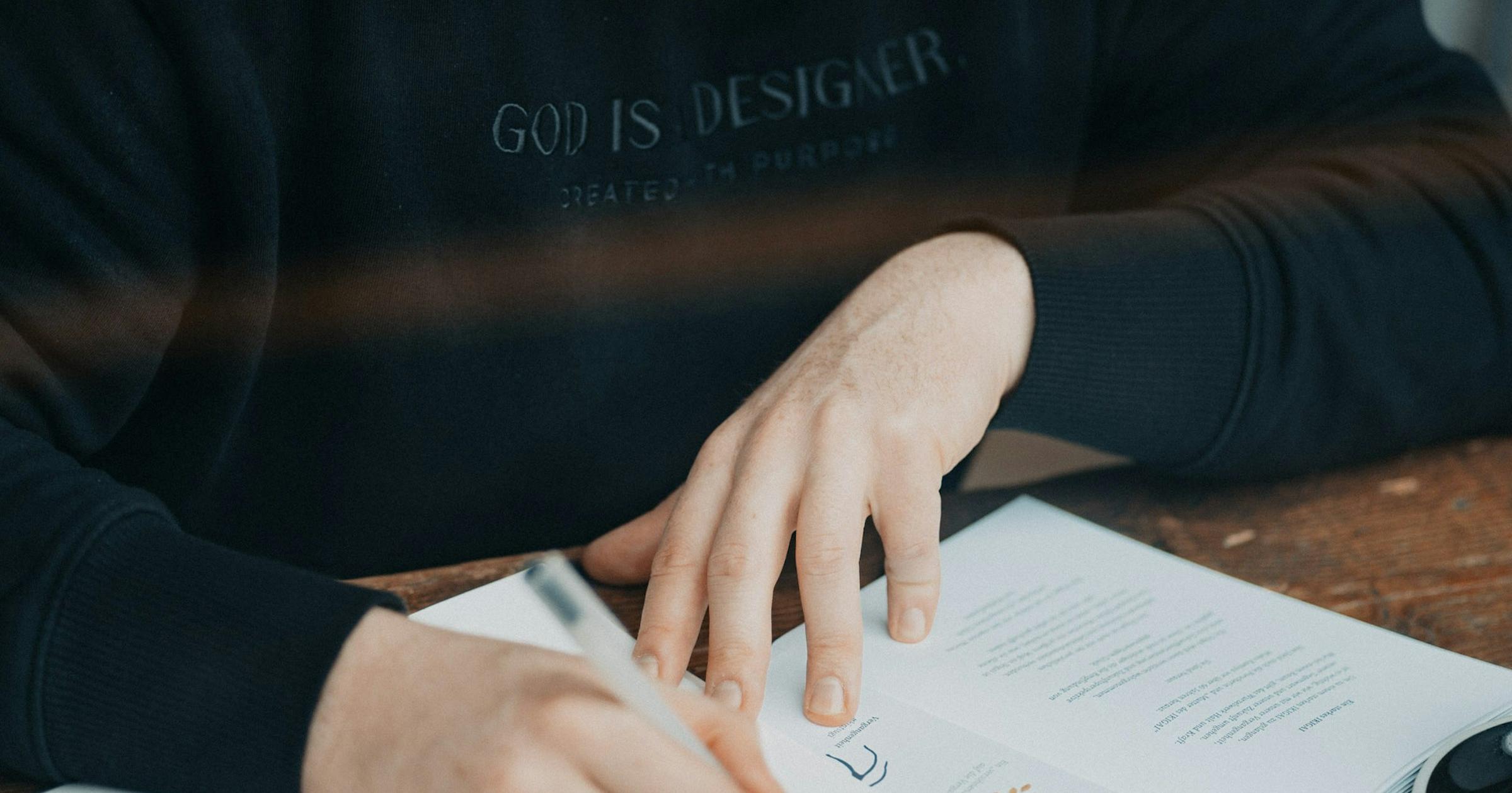 Man writing in a notebook at a café table with a cup of coffee, planning his next steps