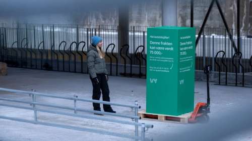 Kvinne ser på stor grønn boks med budskap fra Vy