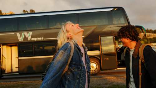 To unge voksne smiler og ler foran Vy express