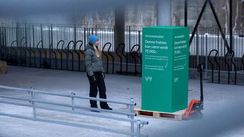 Kvinne ser på stor grønn boks med budskap fra Vy