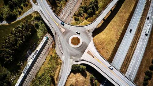Dronefoto av veier og togskinner med trafikk