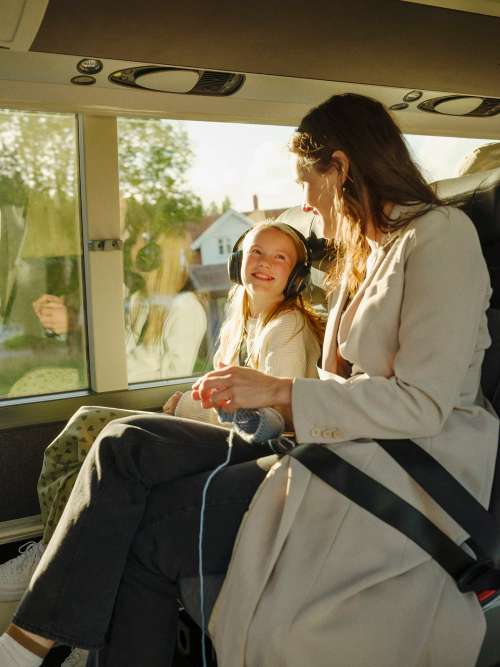 Mor og datter smiler til hverandre om bord på buss