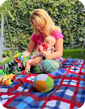 Eine blonde Frau die in einem Garten mit einem Baby spielt