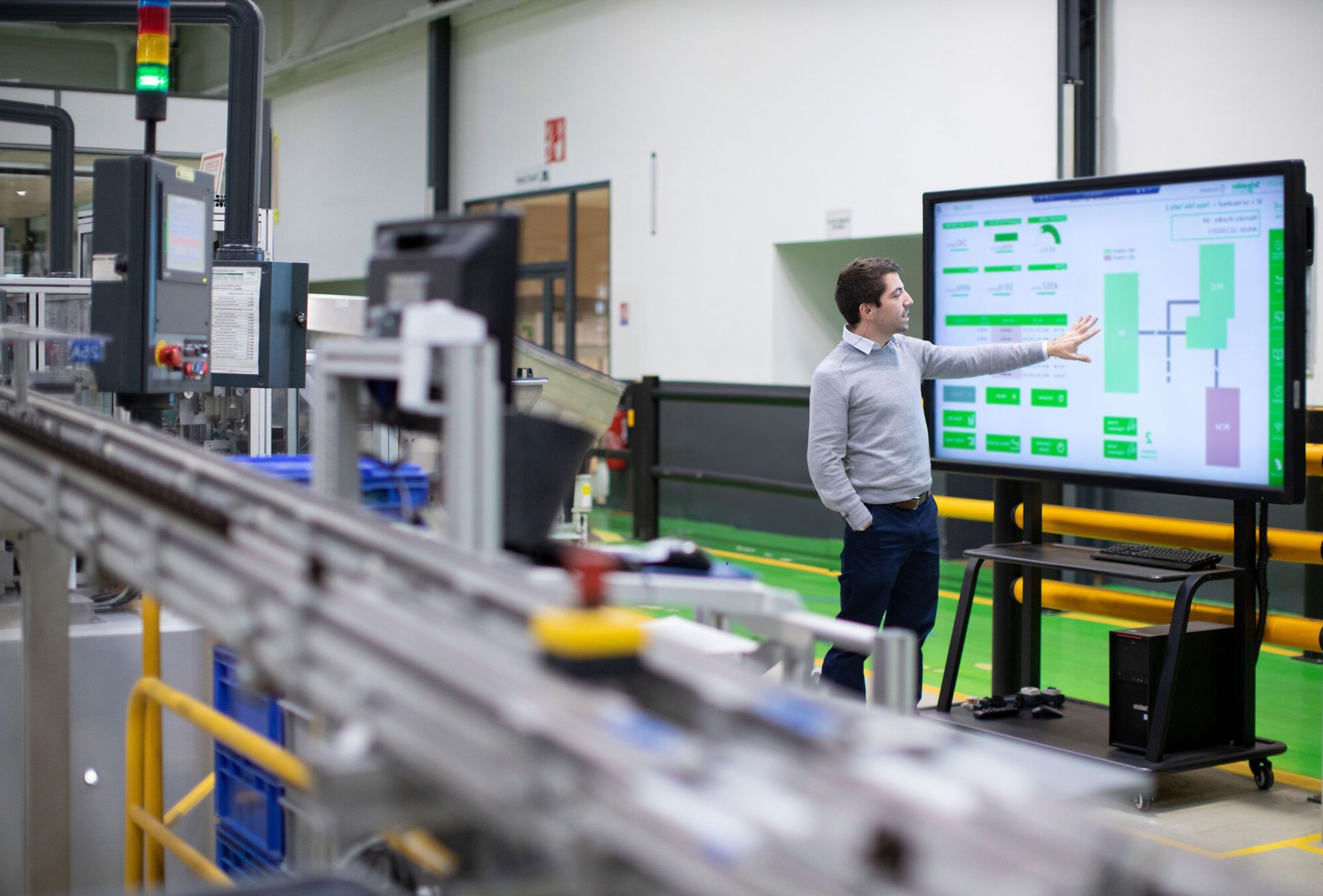 Engineer using large industrial HMI to supervise and control manufacturing processes in a modern factory environment.