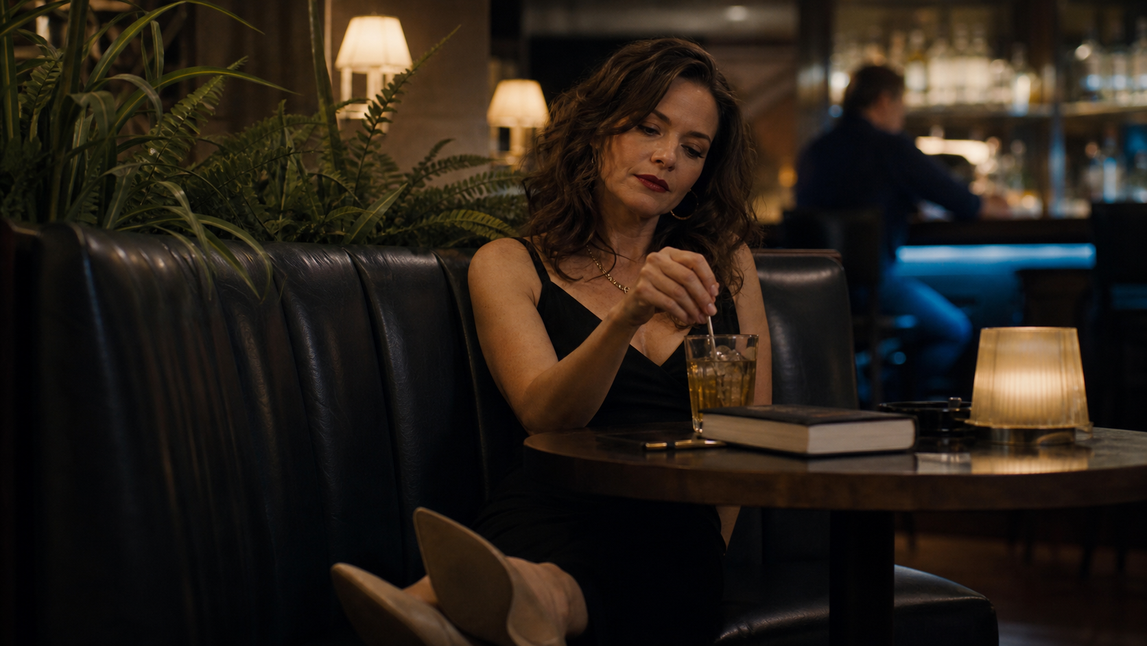 Modern Delilah in a dim motel lounge booth, lipstick intact, heels off, stirring a drink in tired glamour.