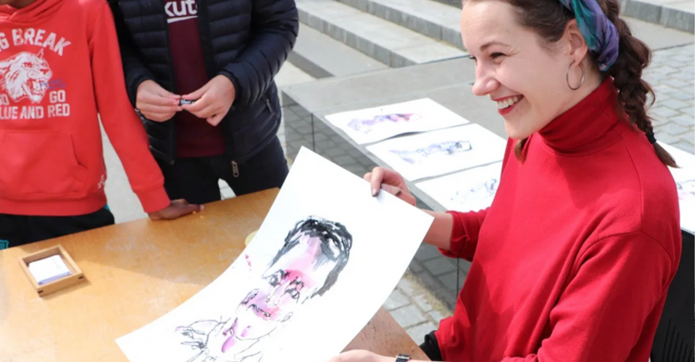 Iris showing a guest their blind-drawn portrait