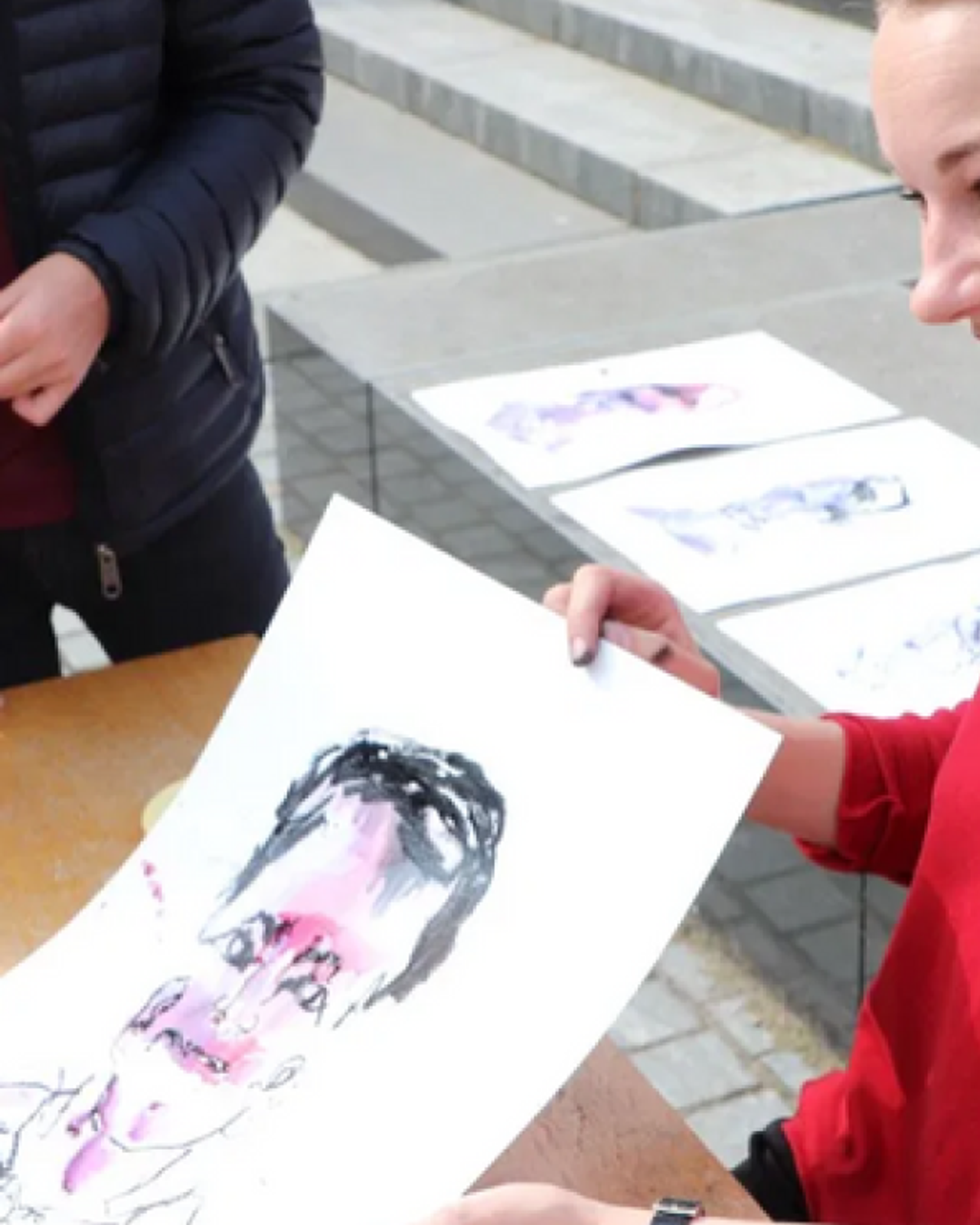 Iris showing a guest their blind-drawn portrait