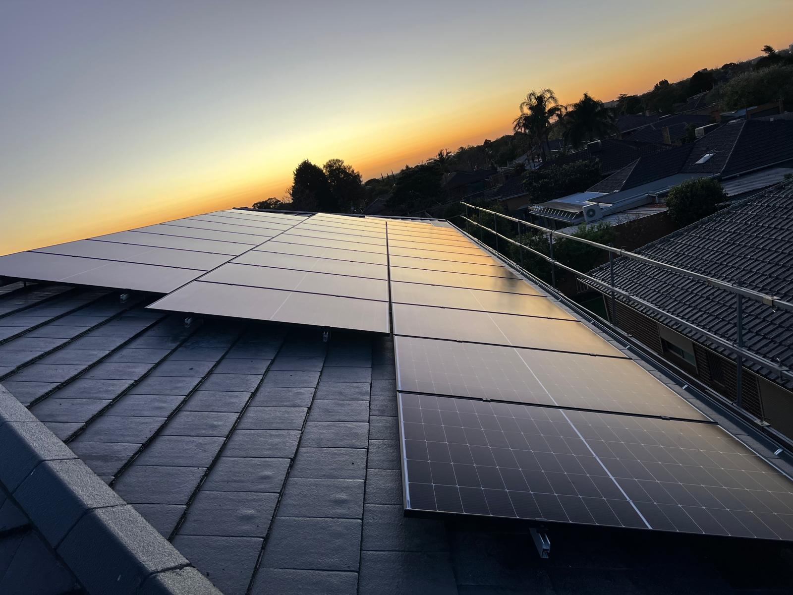 Solar panels installed on a residential tiled roof at sunset in suburban Melbourne