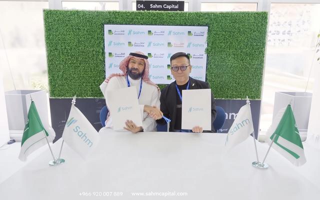 Dr. Adnan Alkhiary, Founder of Eddekhar, and Steven Chou, Chairman of Sahm Capital, shake hands while holding signed partnership documents in front of a step-and-repeat backdrop with the Eddekhar and Sahm Capital logos.