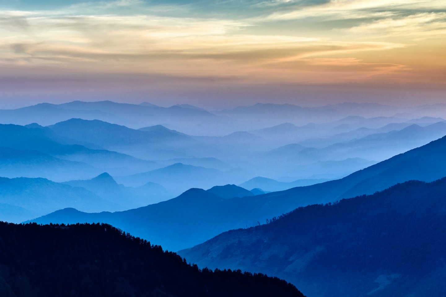 Layered blue mountain ridges fading into haze at dusk