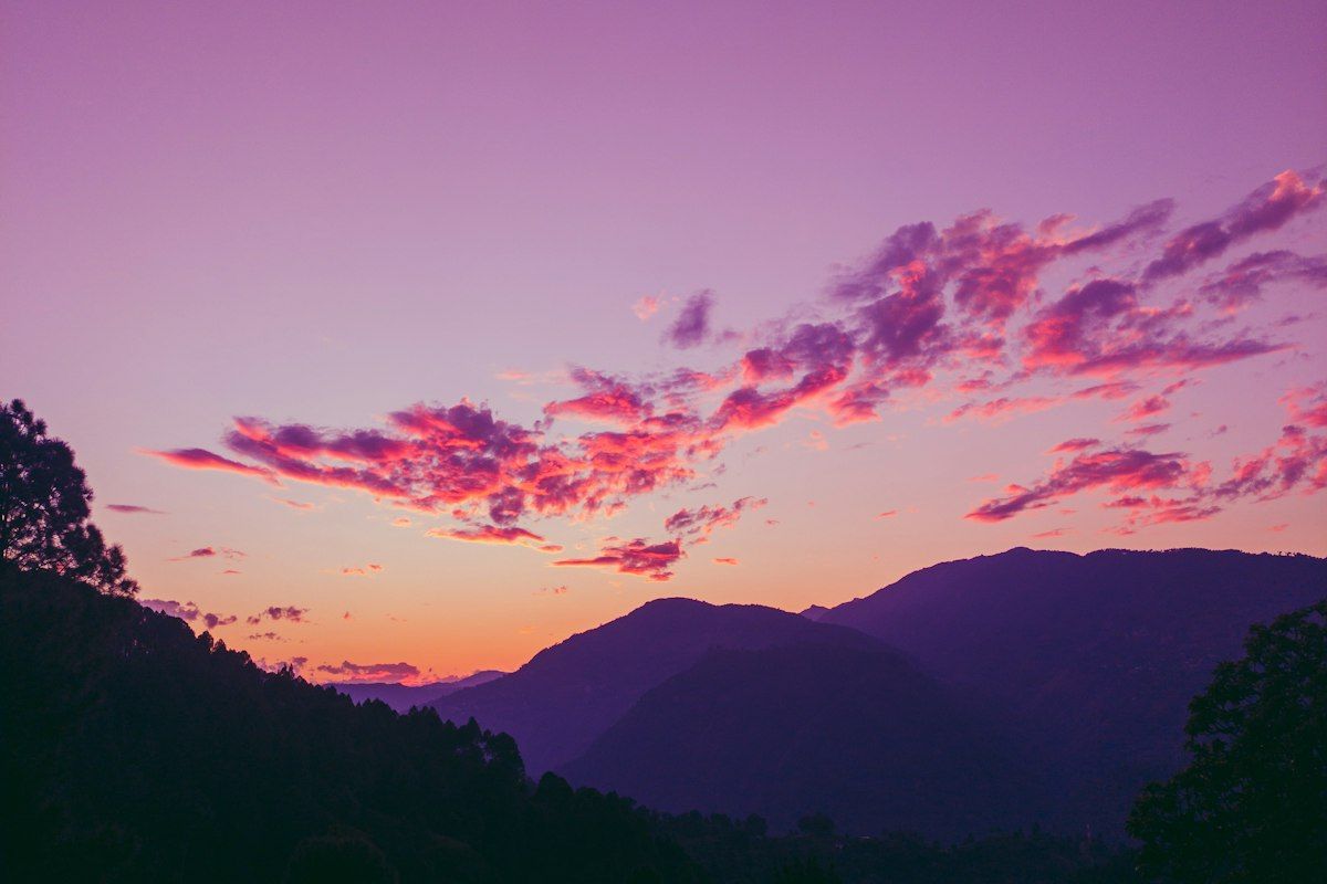 Purple sky with pink clouds over mountains at dusk