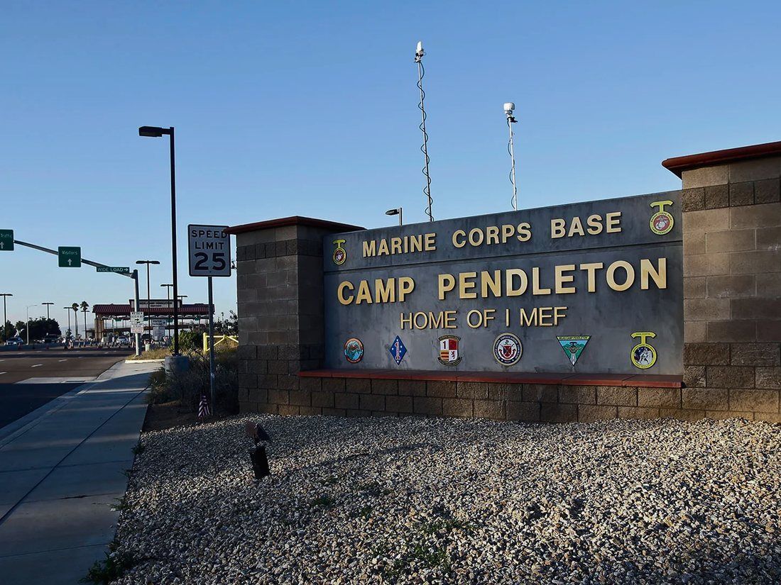 The entrance sign at Marine Corps Base Camp Pendleton beneath a clear blue sky