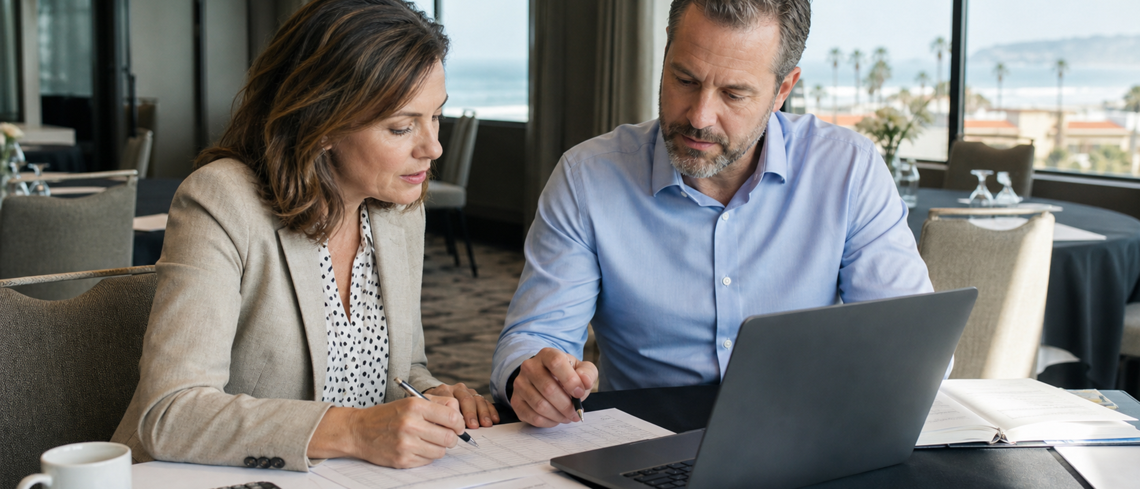 An event planner and finance partner review a corporate offsite budget in a San Diego meeting venue