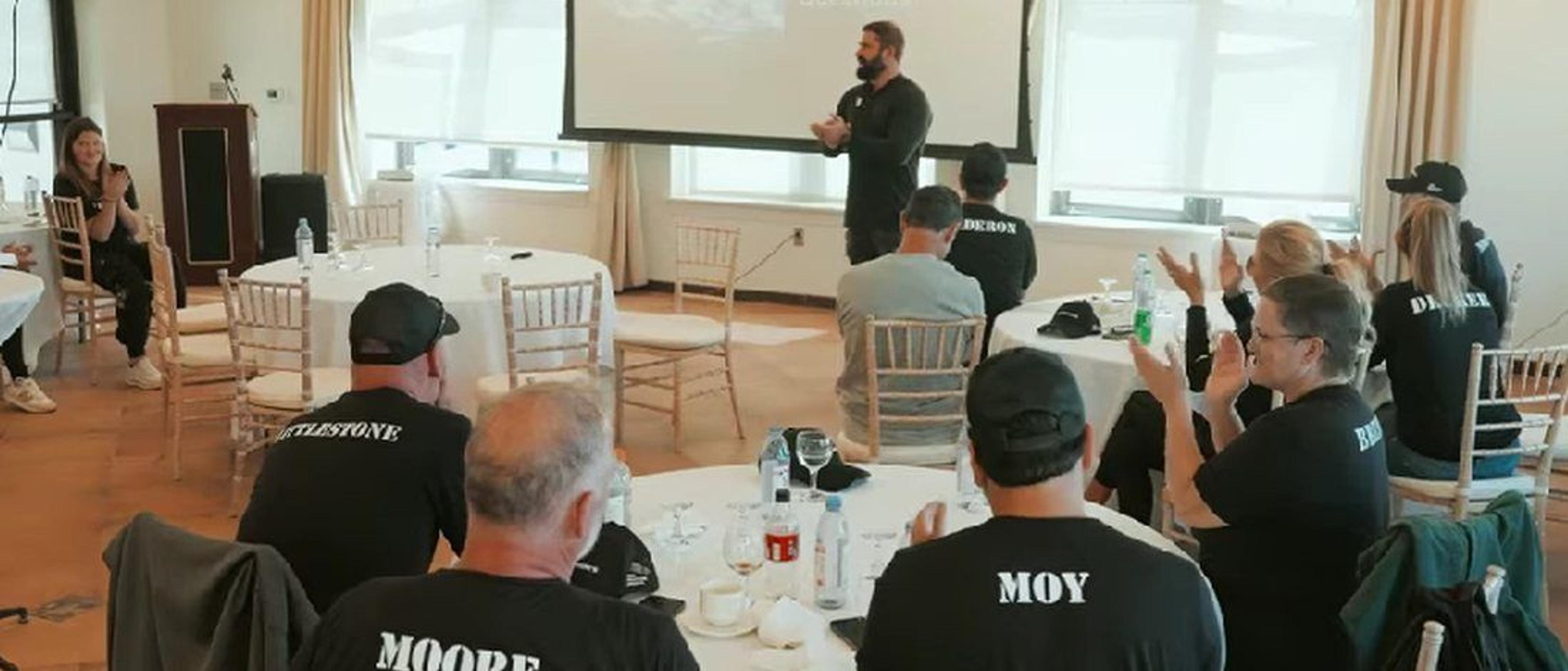 A speaker addresses guests seated around tables during a Camp Pendleton event