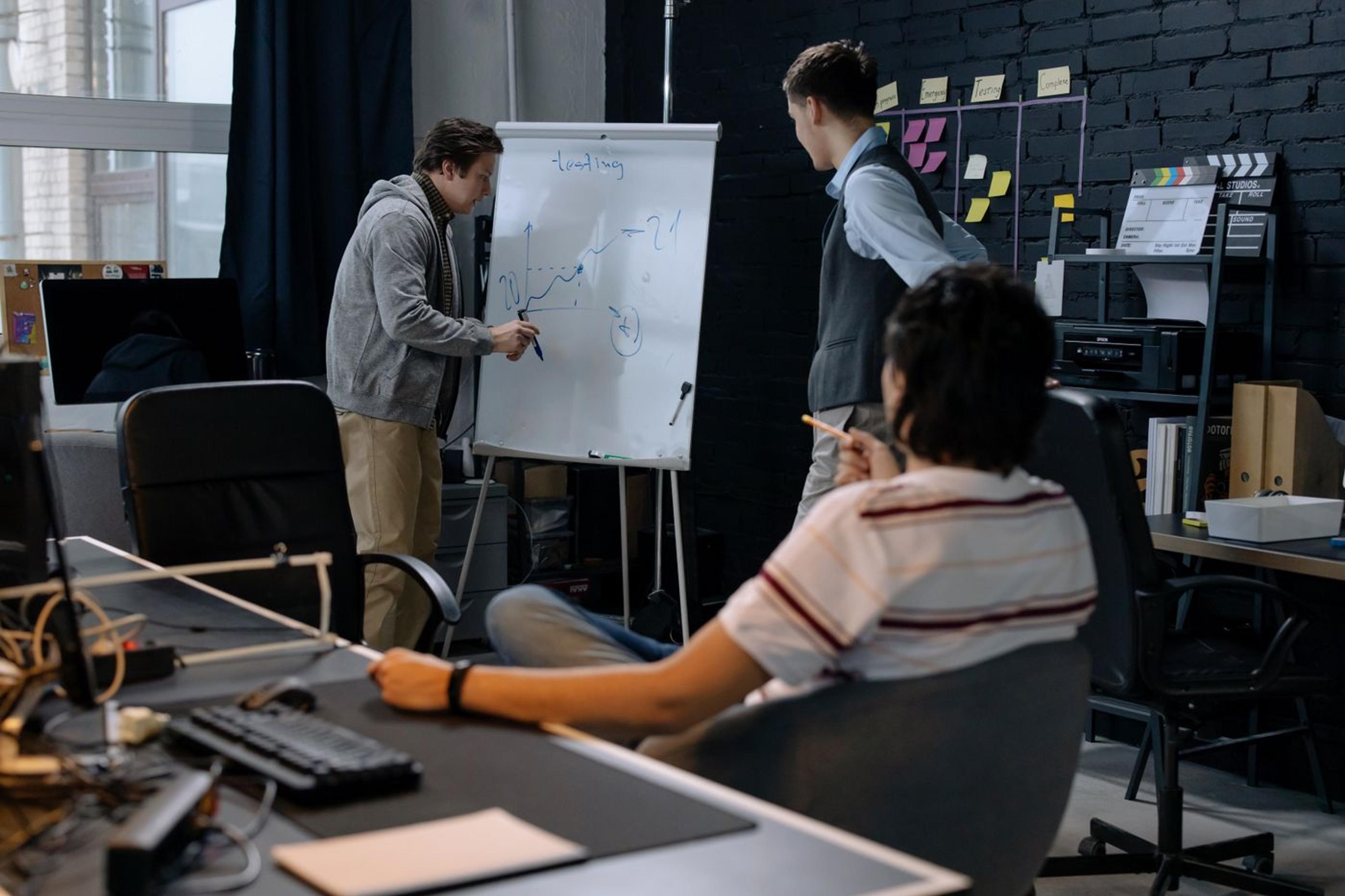 Colleagues sitting together and discussing notes on a whiteboard