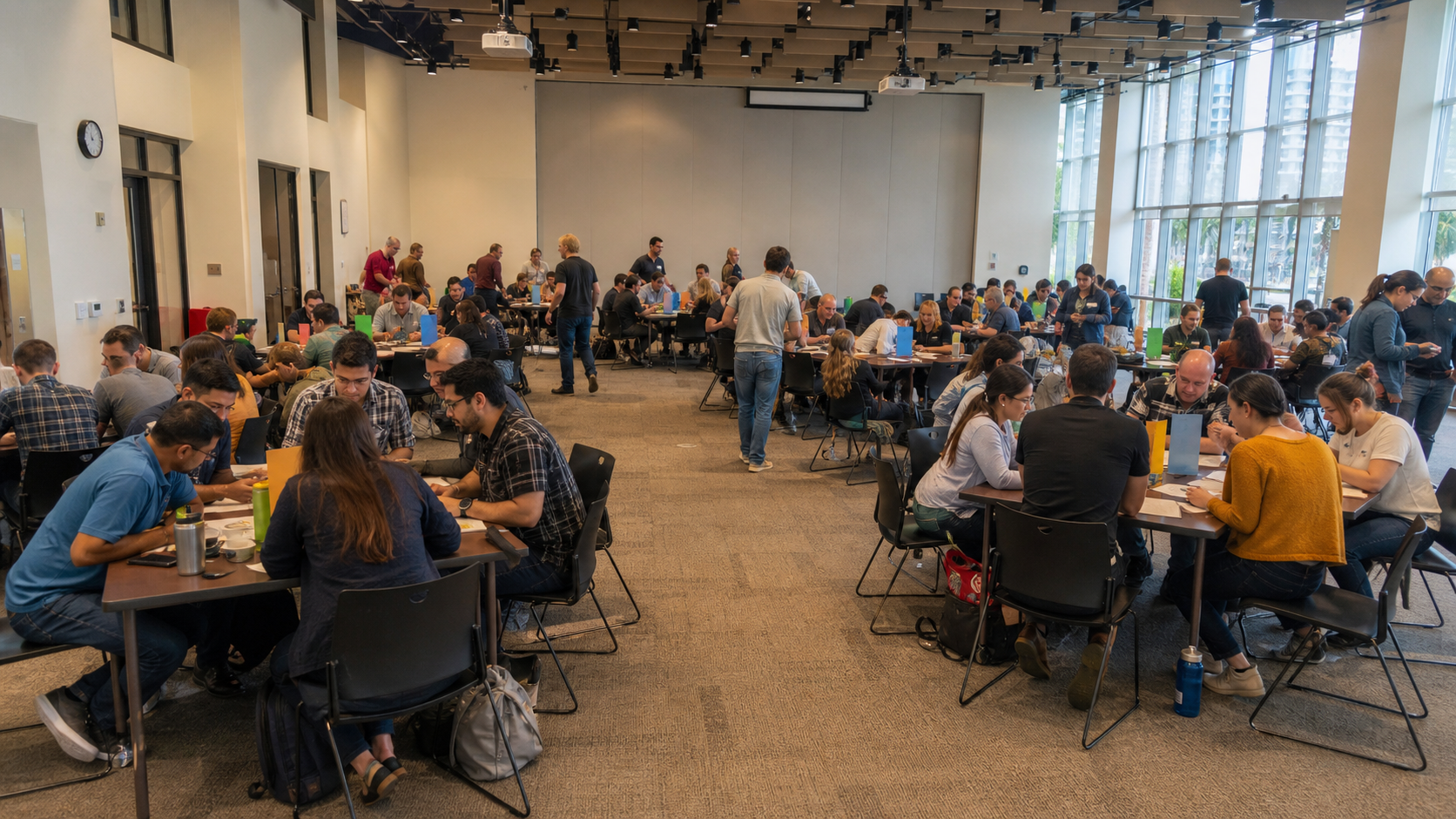 A large workplace group rotates through facilitated activity stations outdoors
