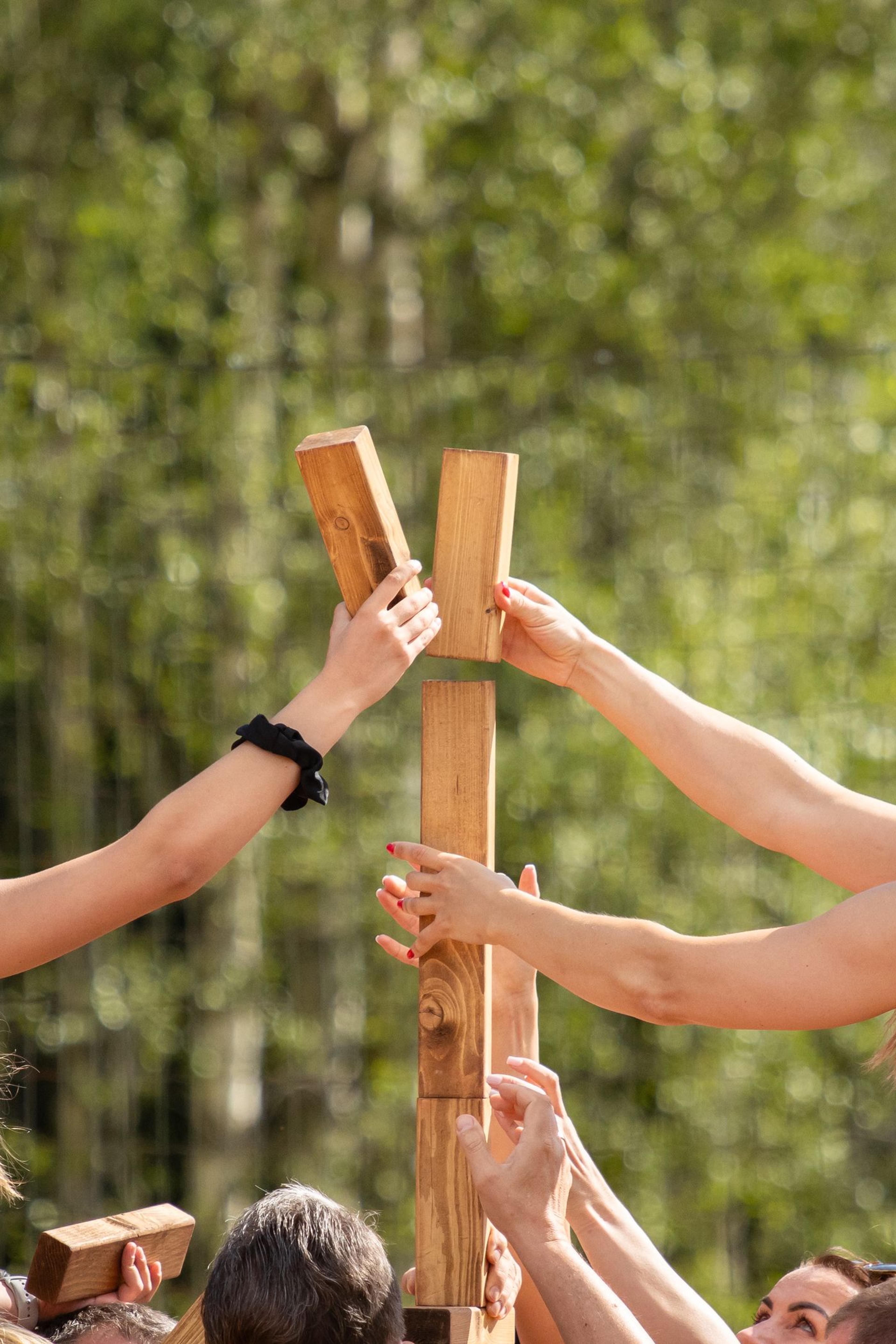 Participants working together on a wooden block tower outdoors