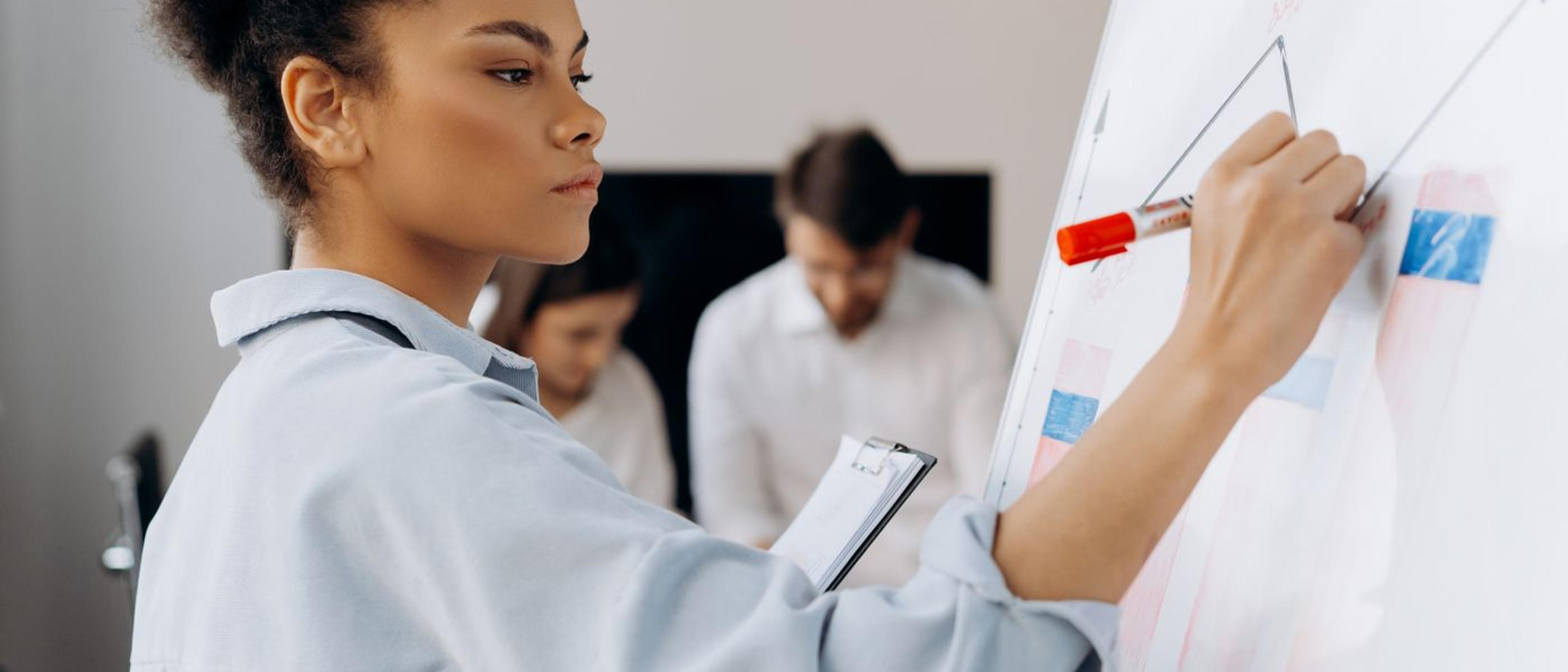 A colleague leading a discussion at a whiteboard while teammates listen
