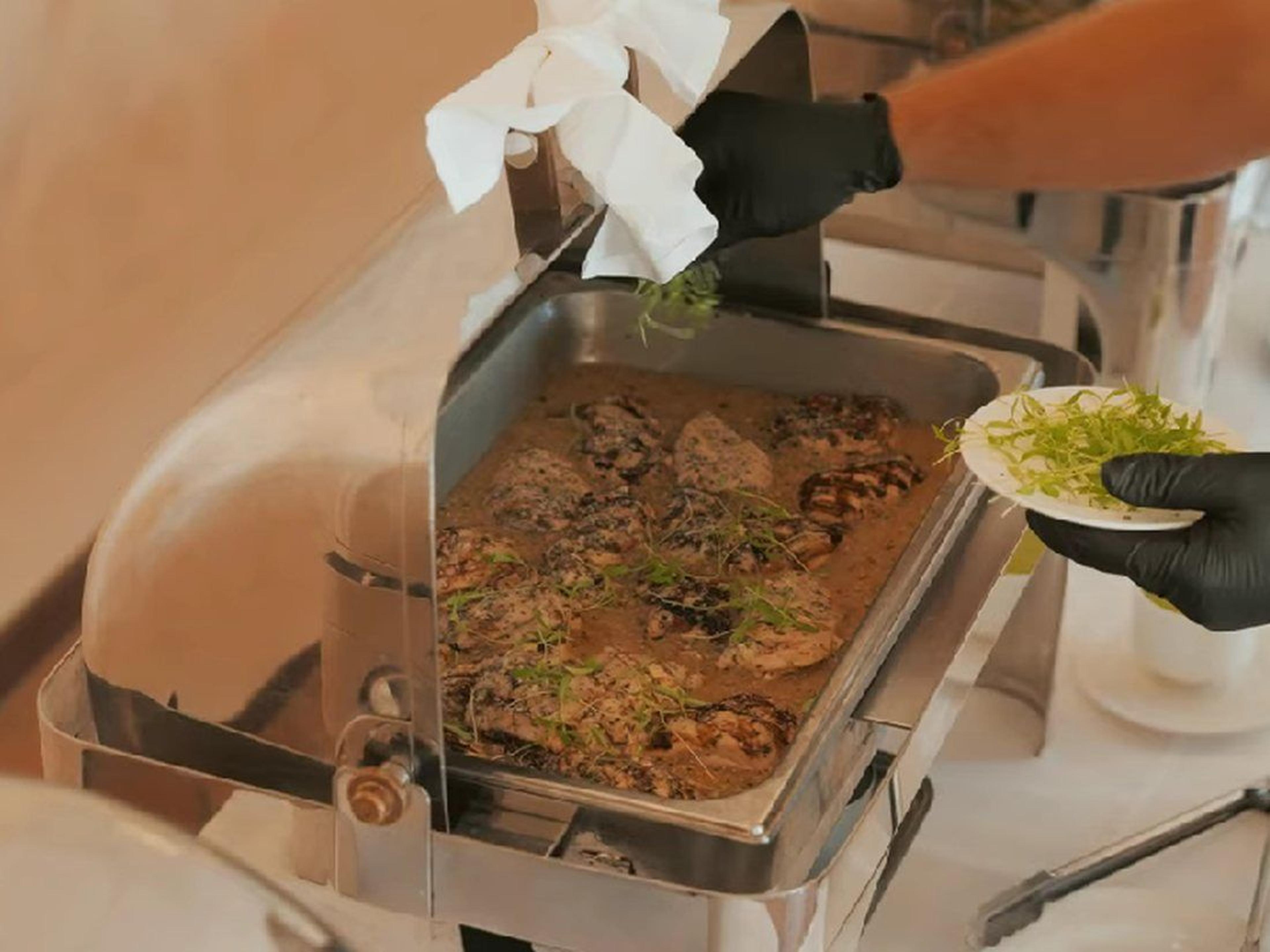 A catering team member serves food onto a plate at a Camp Pendleton event