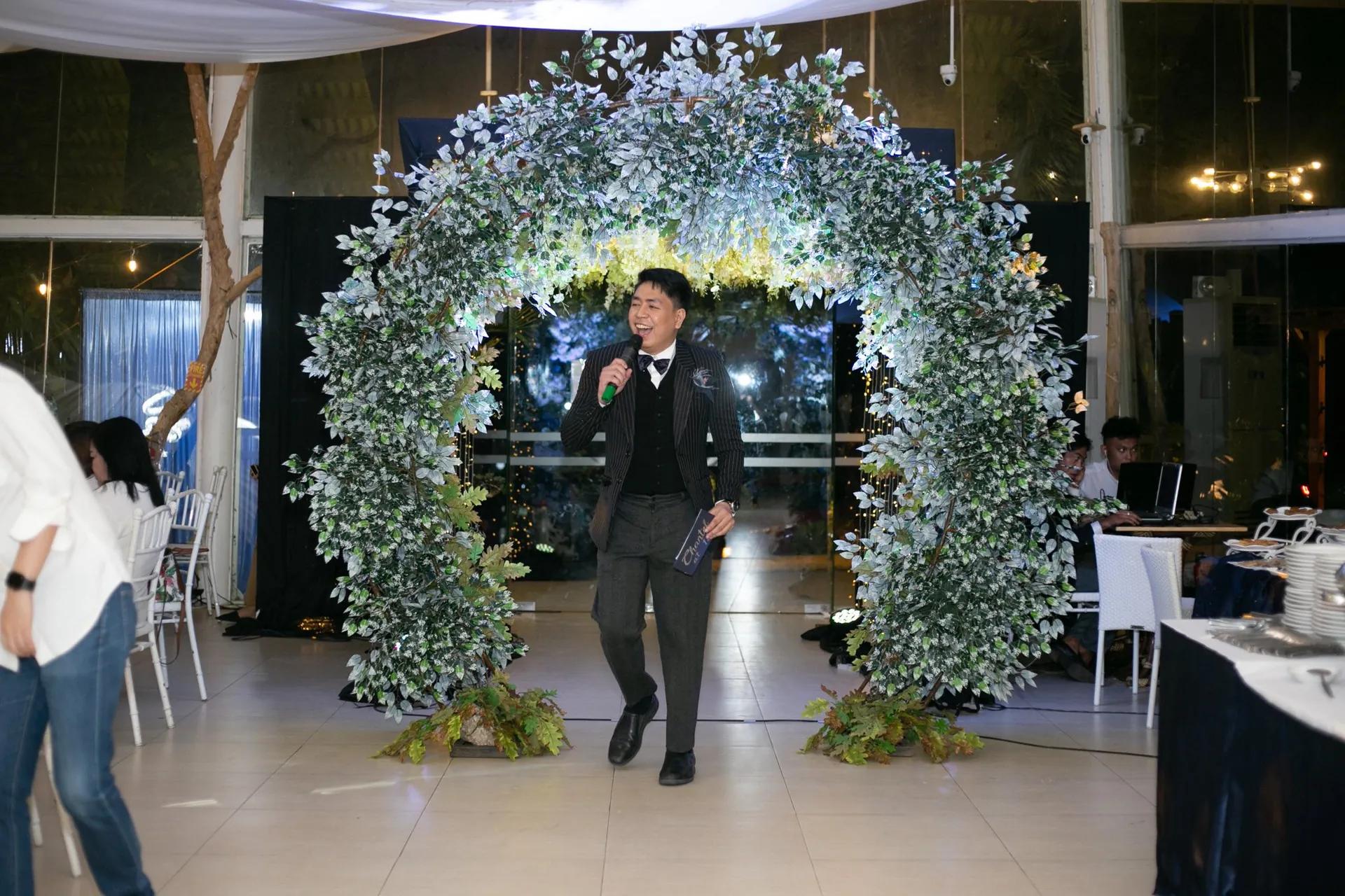A wedding emcee under a floral arch at a reception in the Philippines