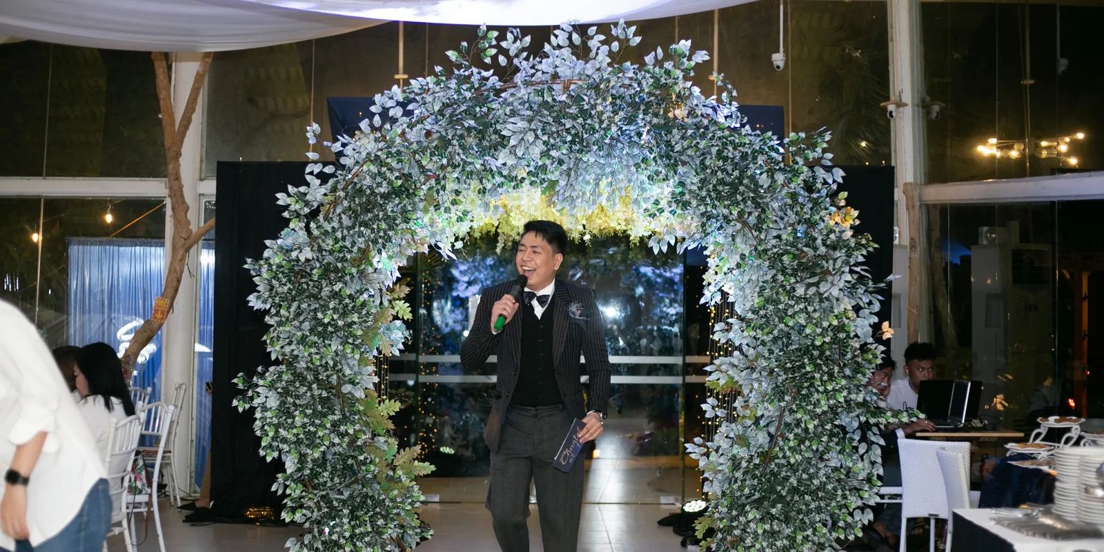 A wedding emcee under a floral arch at a reception in the Philippines