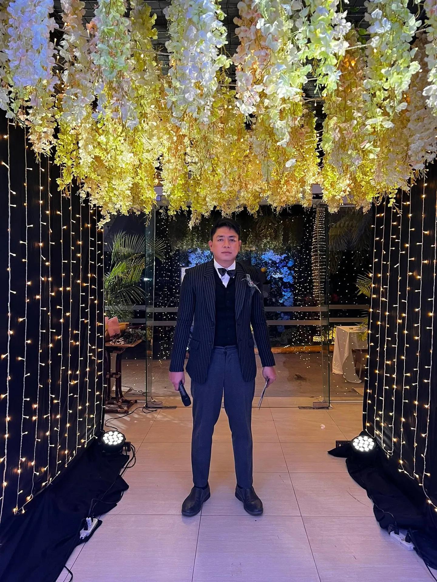 An event host at the entrance of a celebration lit with fairy lights in the Philippines