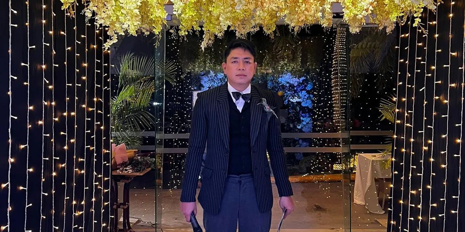 An event host at the entrance of a celebration lit with fairy lights in the Philippines