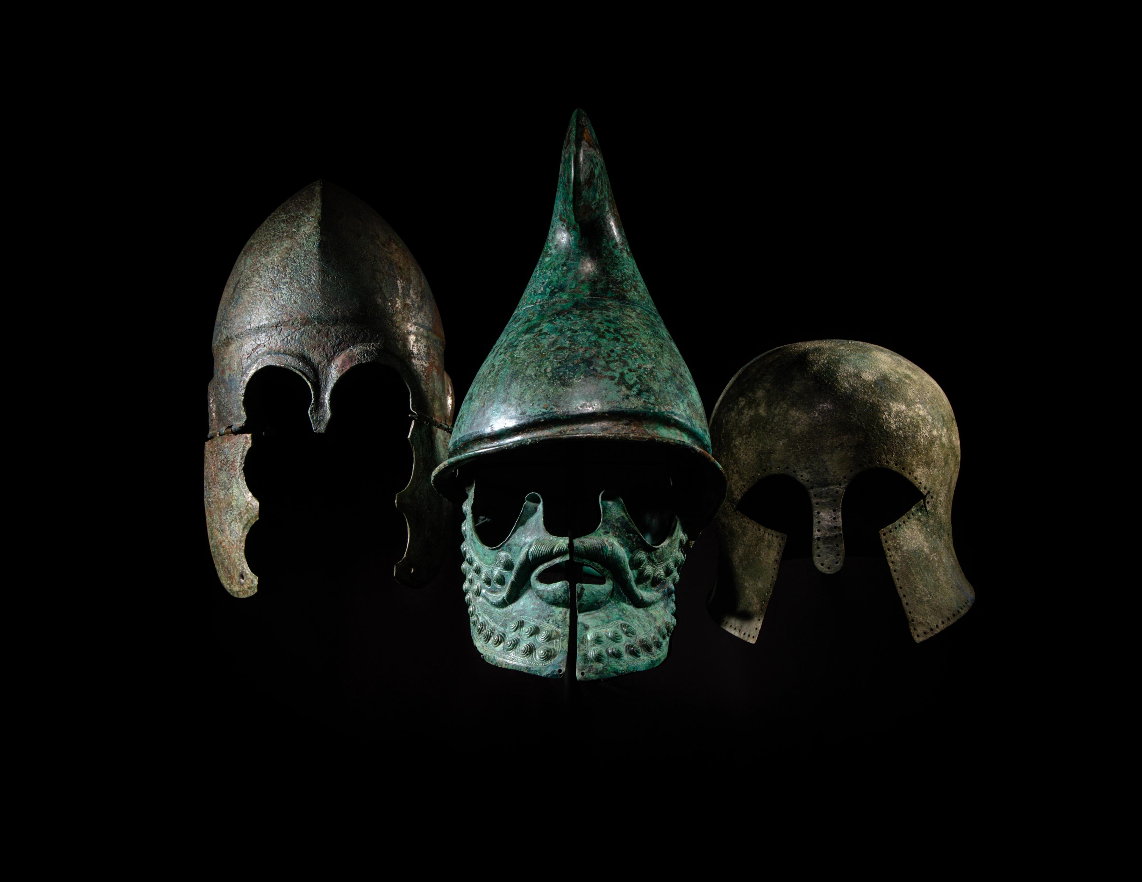 A Greek Tinned-Bronze Chalcidian Helmet (BC 500-301, Estimate: $15,000 – 25,000), Greek Bronze Phrygian Helmet (Circa 350-300 B.C., Estimate: $80,000 – 120,000), and a Greek Bronze Corinthian Helmet (Circa 6th Century B.C., Estimate: $60,000 – 80,000)